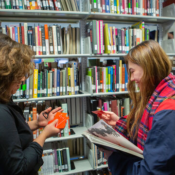 Two students talk and laugh in the library