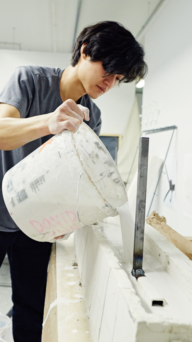 A student pouring plaster into a mold. 