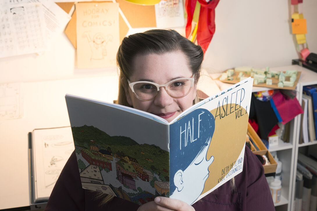 A photo of Beth Hetland holding one of her comics 