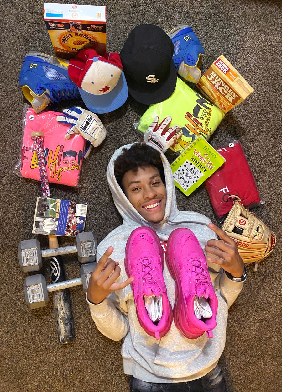 A young student lies on the ground smiling surrounded by weights, sneakers, hats, and snacks