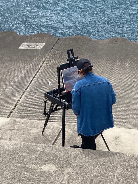 A student paints a lakescape in a city