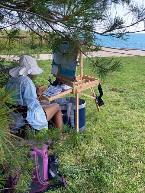 A student painting with an easel by Lake Michigan
