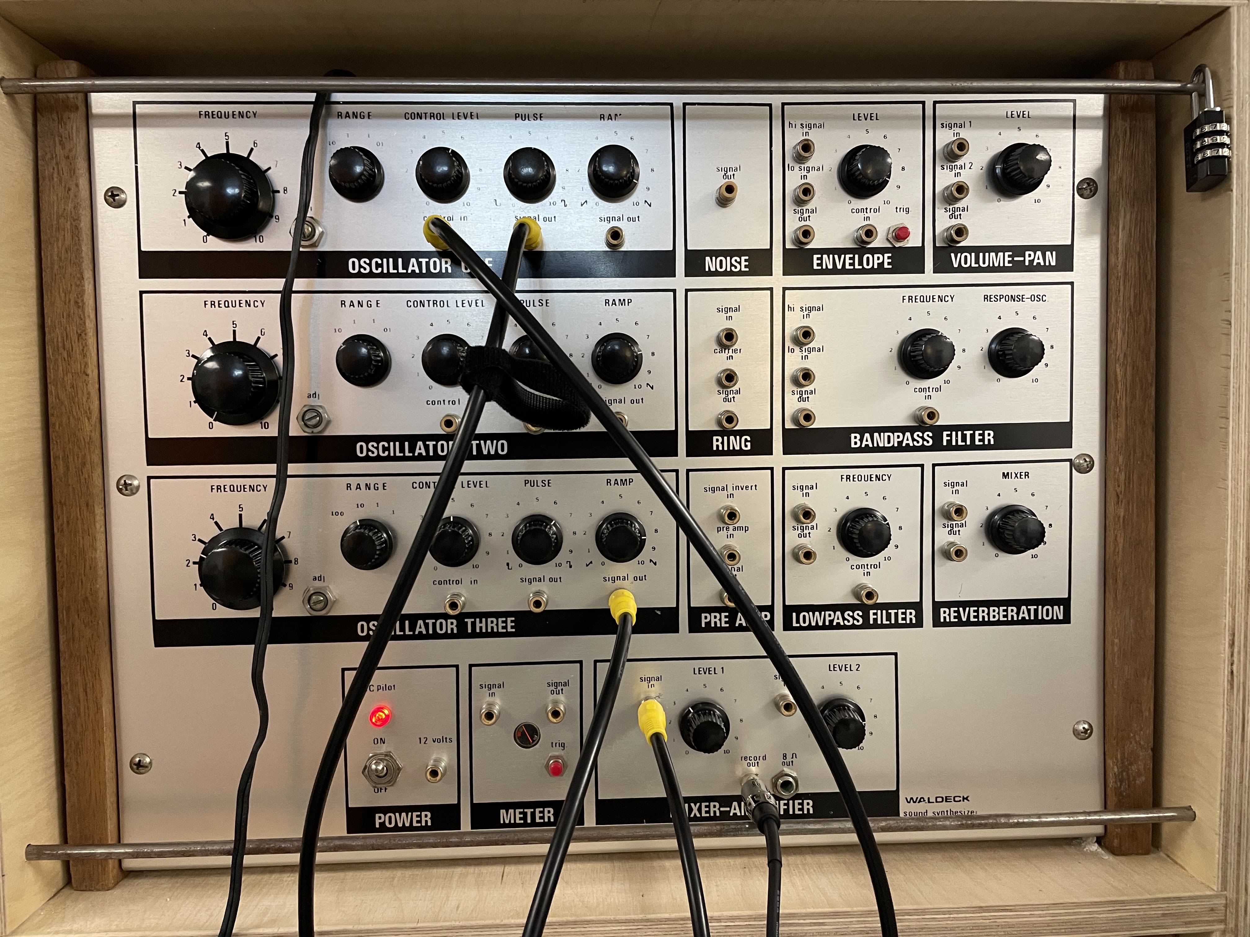 An old, silver synthesizer with black knobs and wires