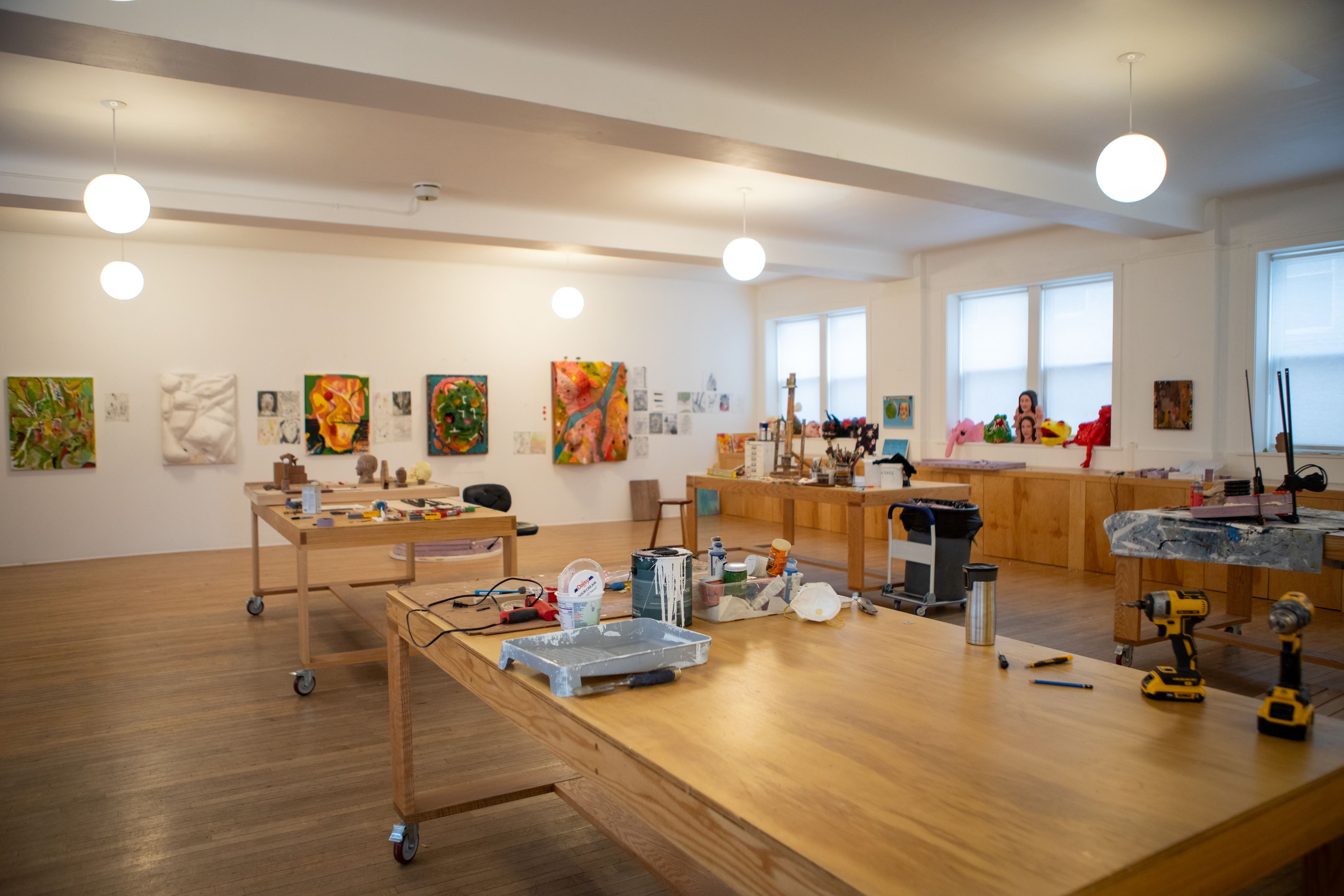 A wood-floored studio space with large tables and colorful art