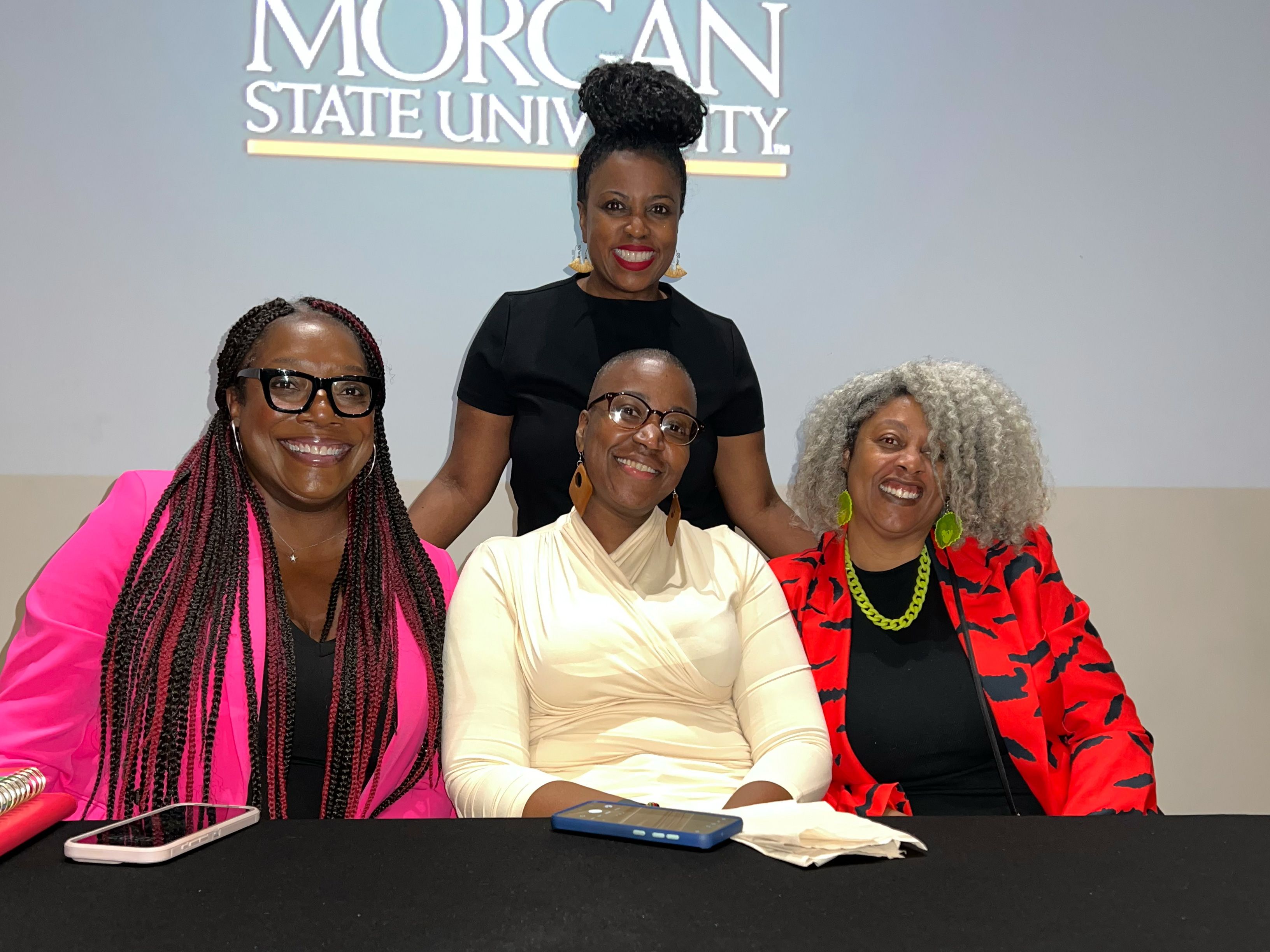 Four women stand in front of a screen saying Morgan State University