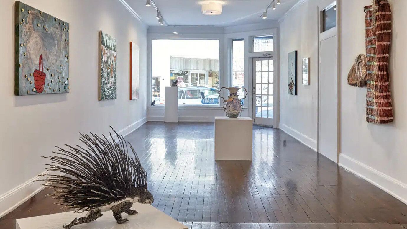 A gallery space with a statue of a porcupine in the foreground