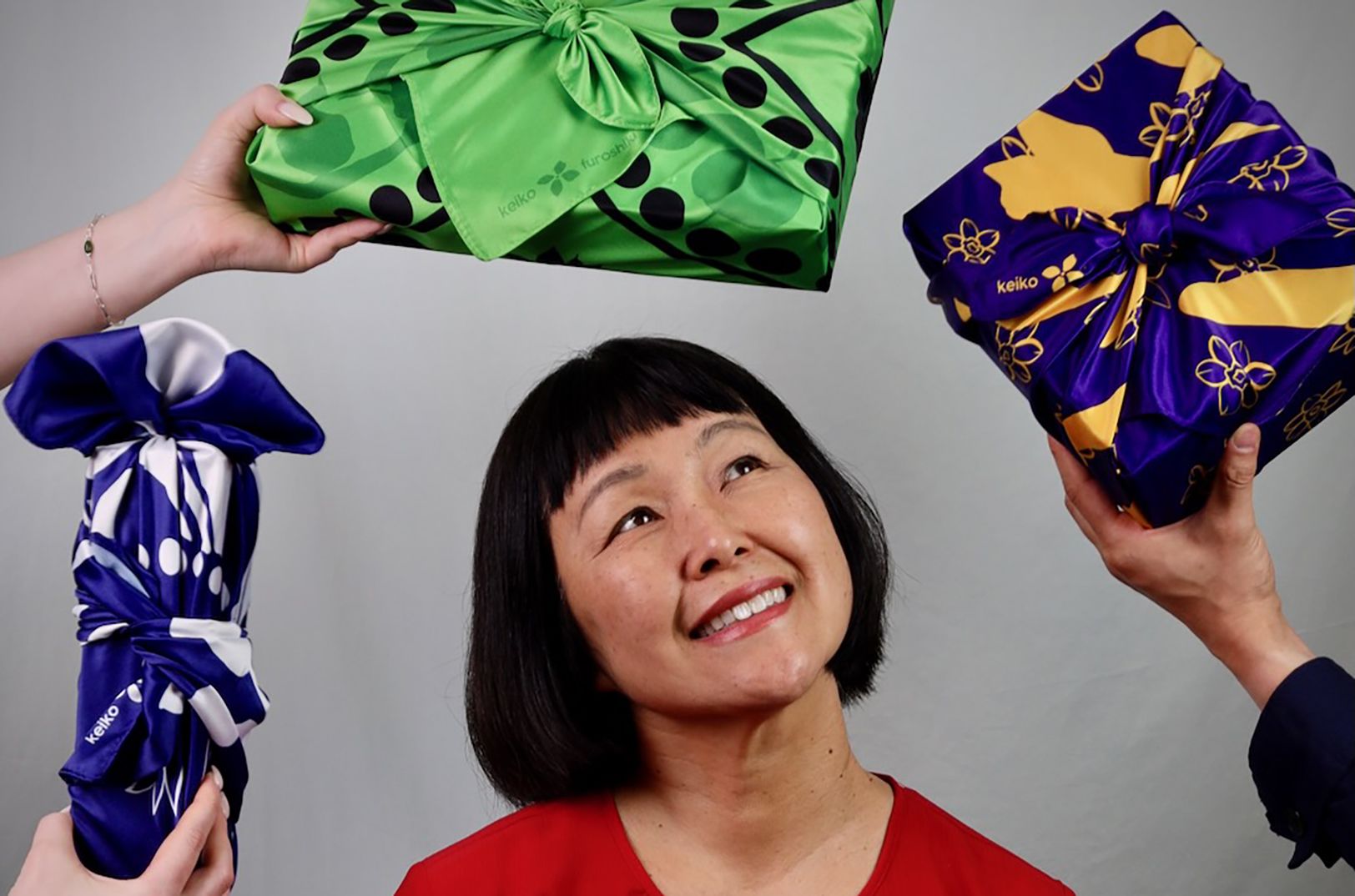 A woman surrounded by gifts wrapped in bright furoshiki fabric