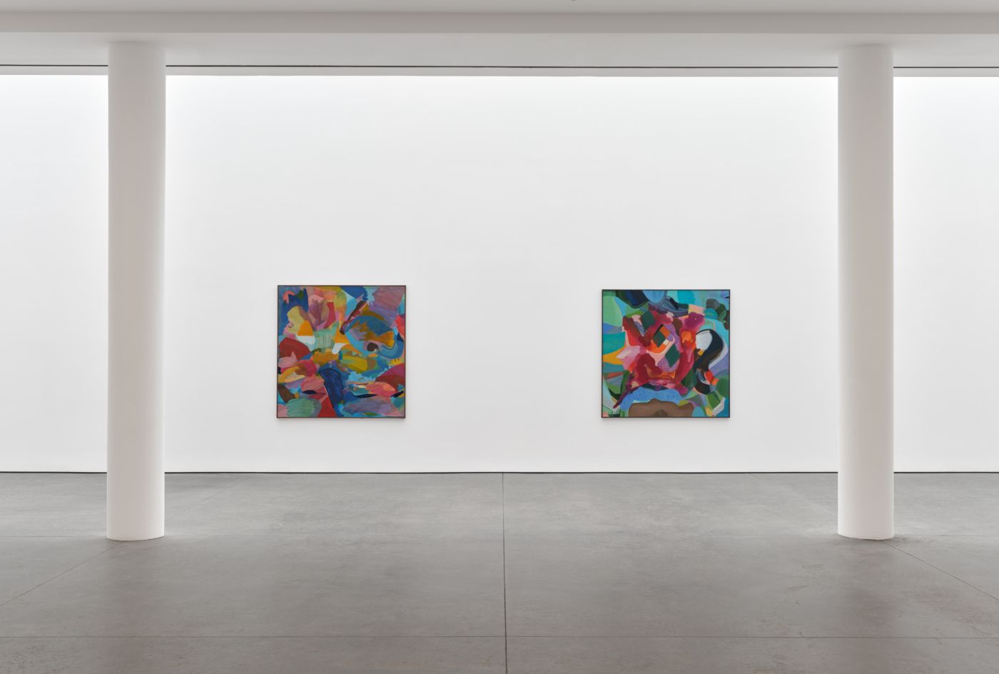 White walls in a gallery space with two bright abstract paintings