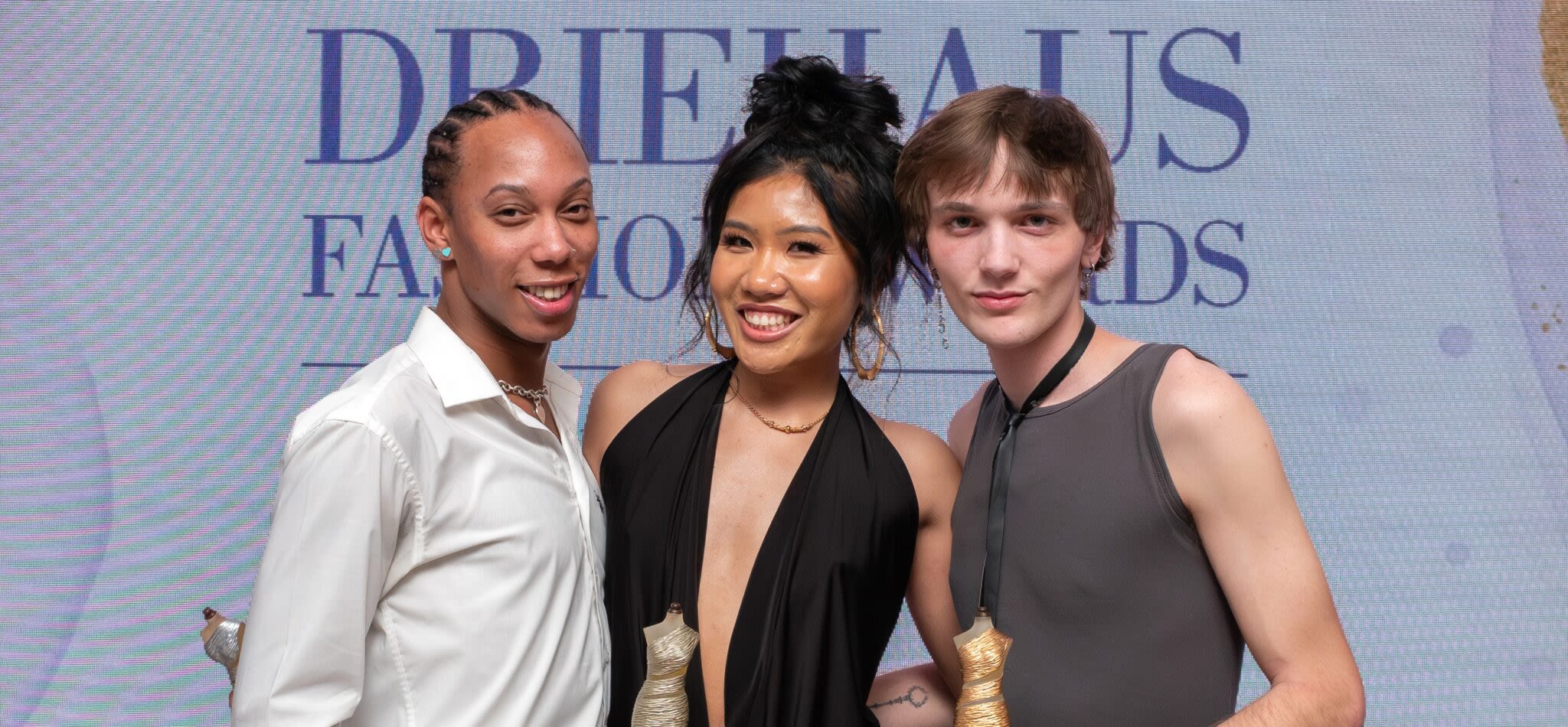 Three artists pose with awards