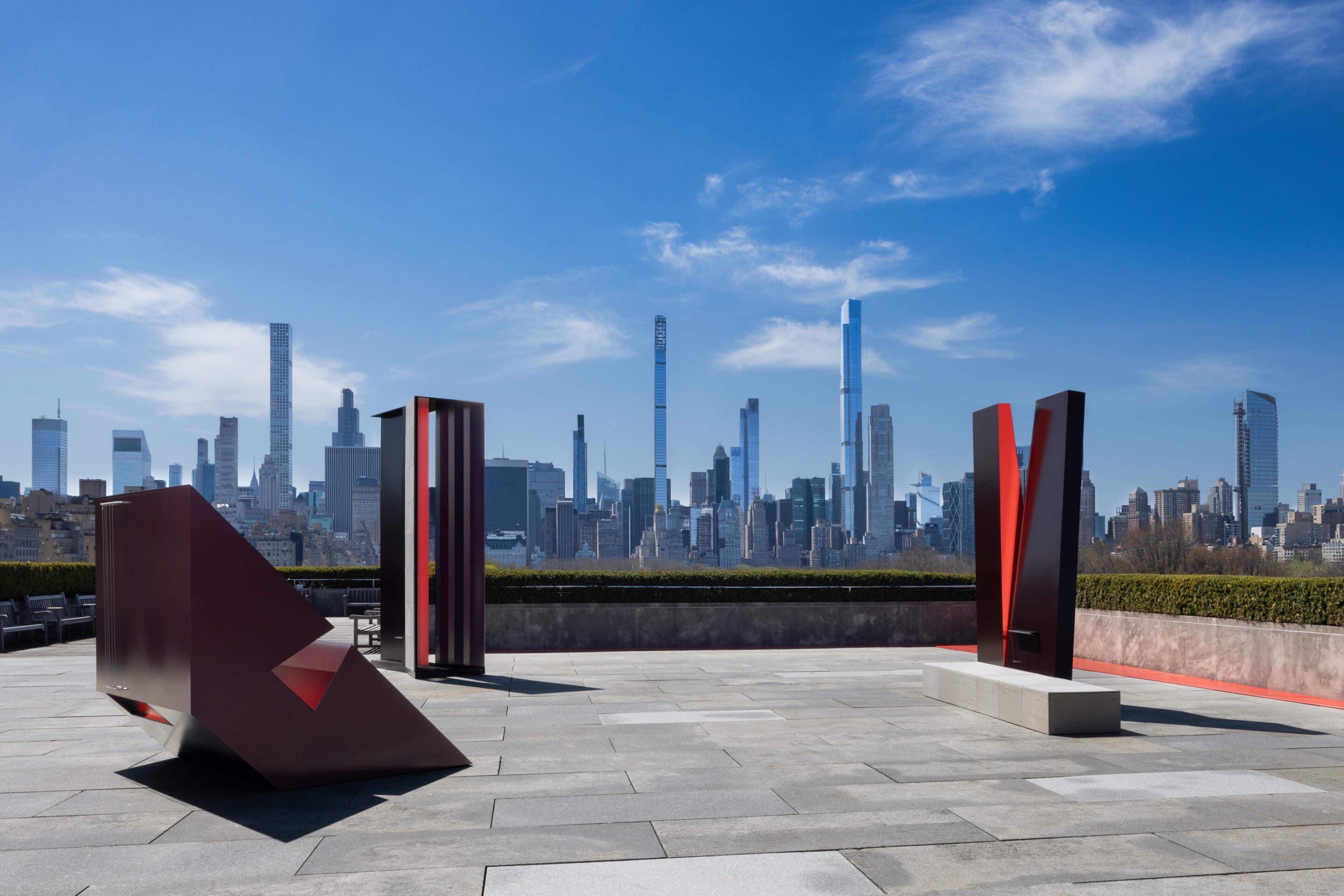 Several black and red sculptures on a roof in New York City.