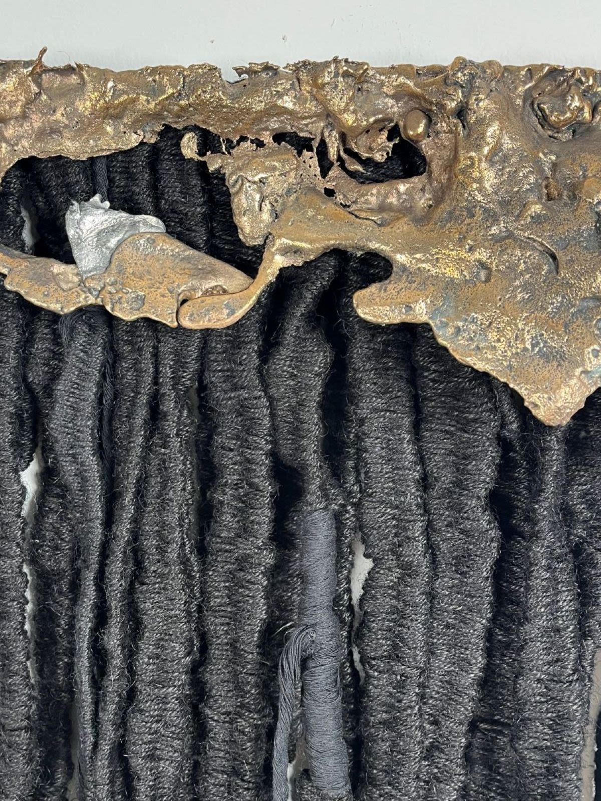 A textile piece with organic metal shapes at the top
