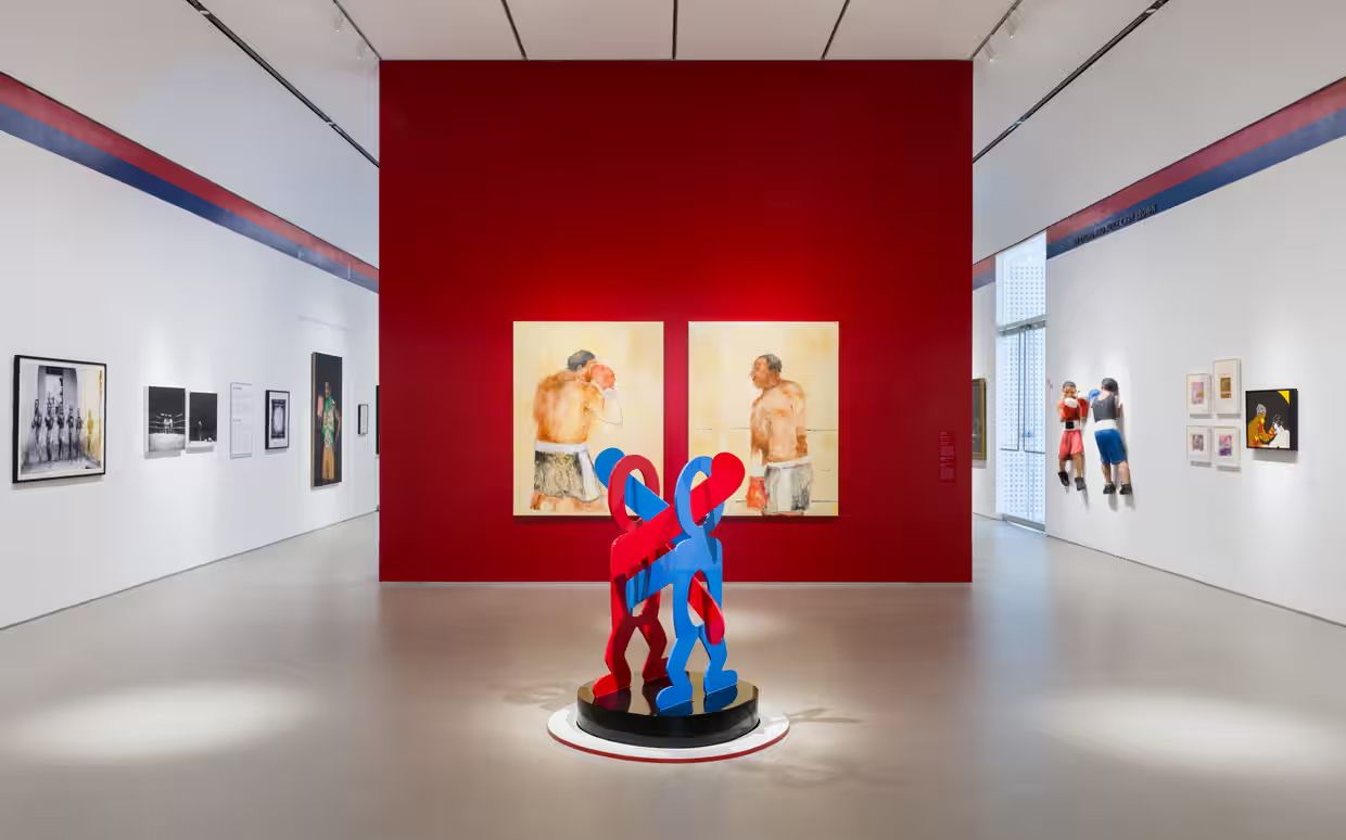 A gallery space with an abstract red and blue sculpture in the foreground