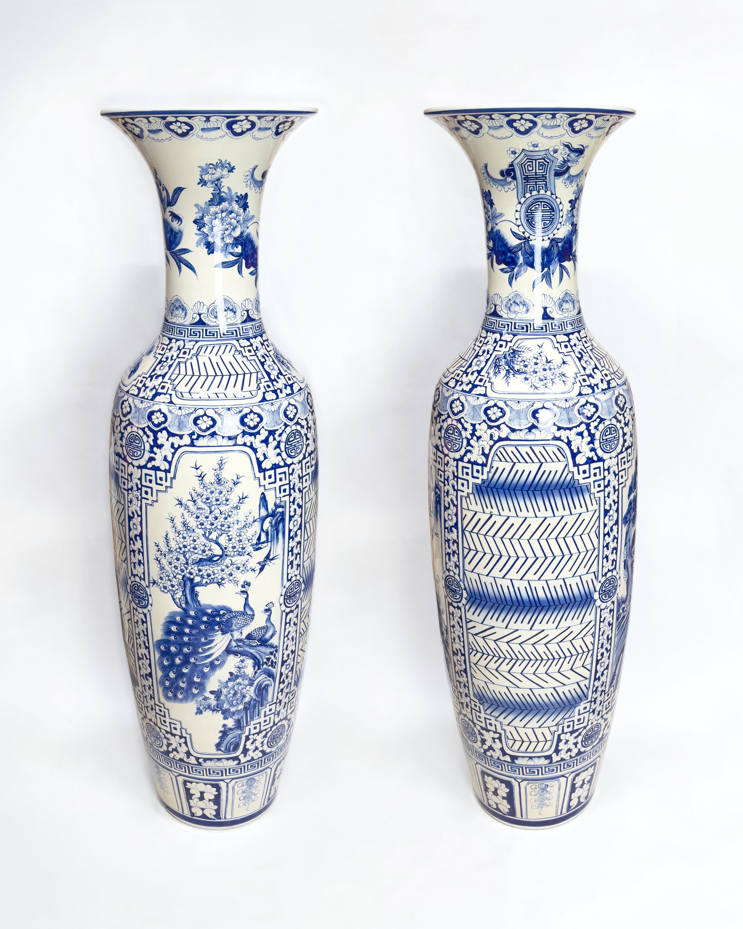Two narrow white vases painted with blue designs
