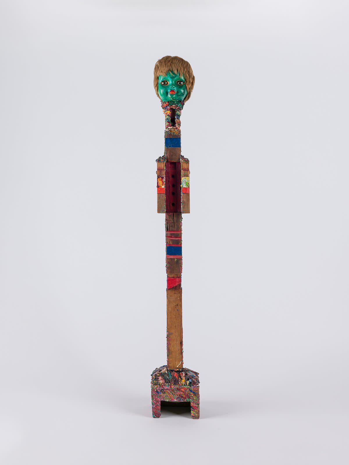 A long, narrow sculpture with a green baby head at the top.