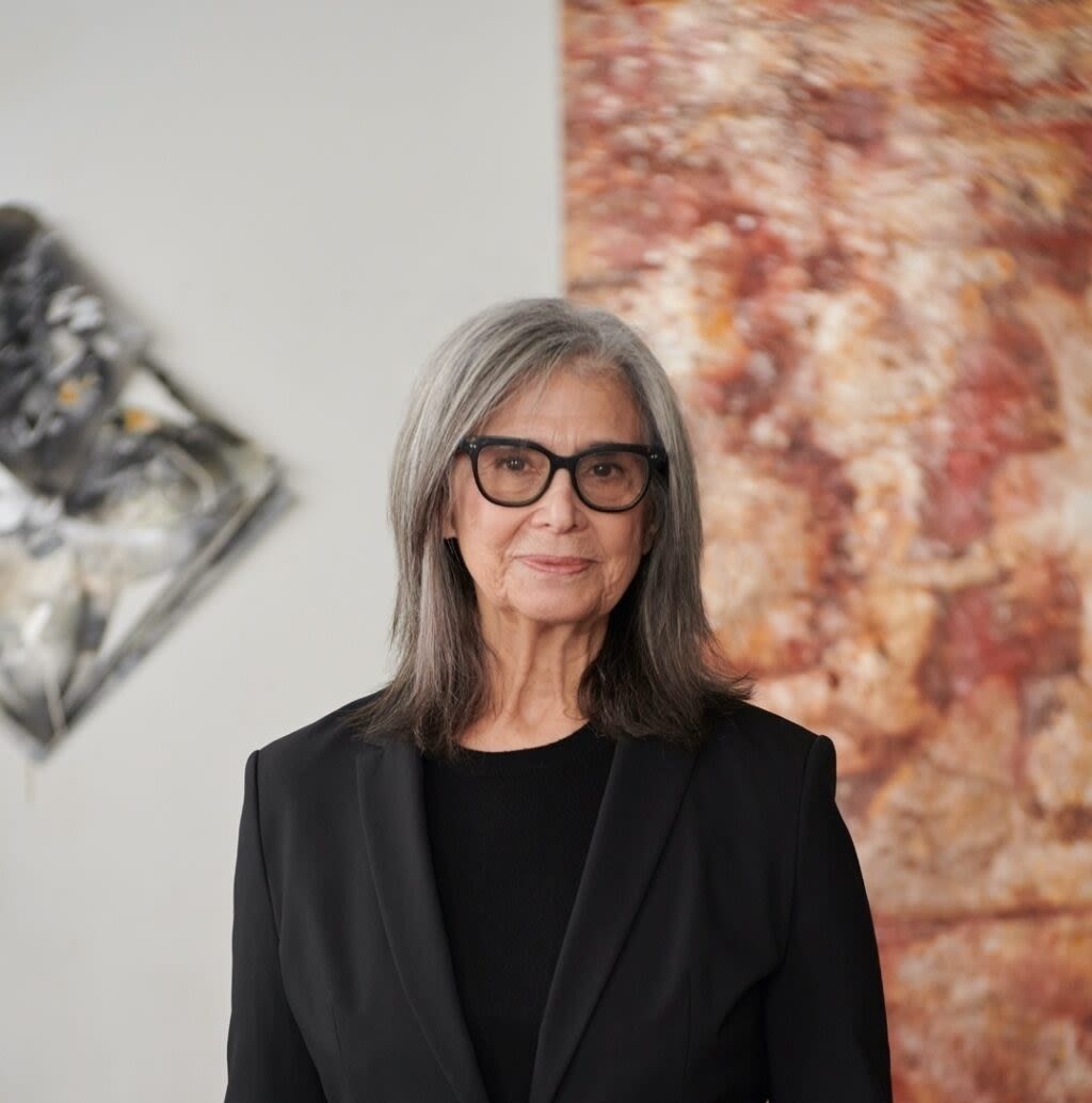 Judith Geichman stands in front of two paintings