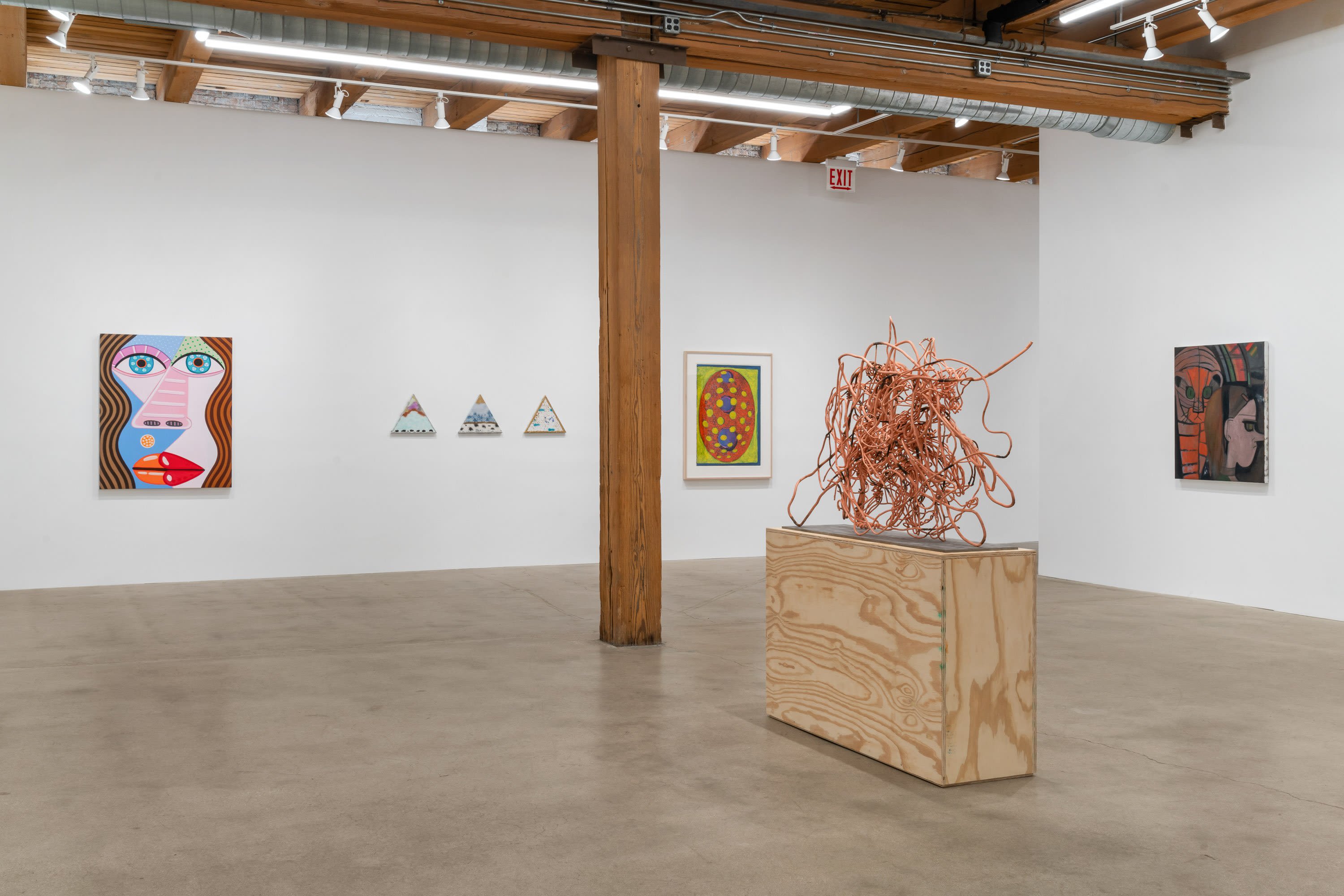 A gallery installation with several paintings and a sculpture
