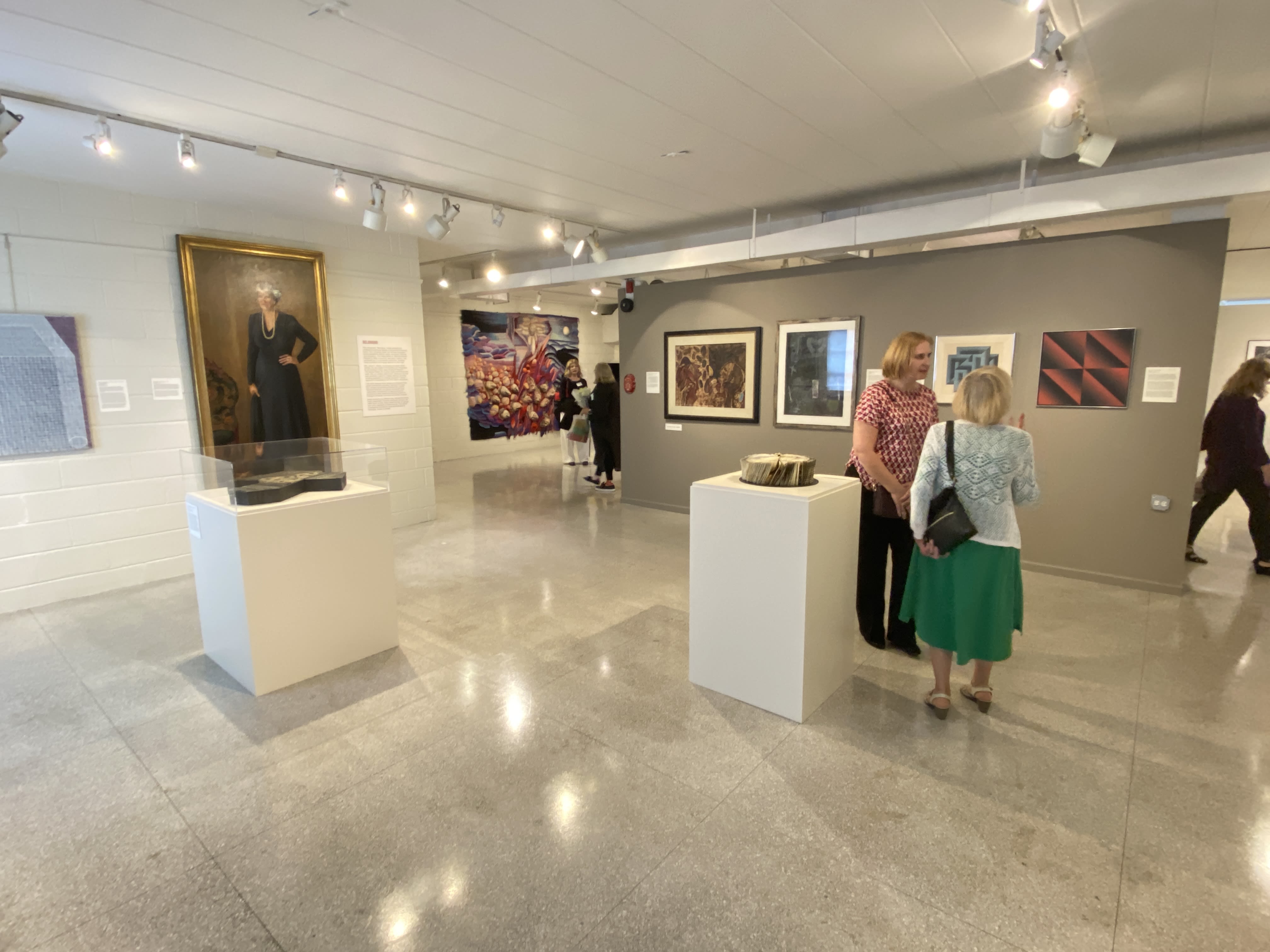 Visitors standing in a gallery with many paintings and sculptures