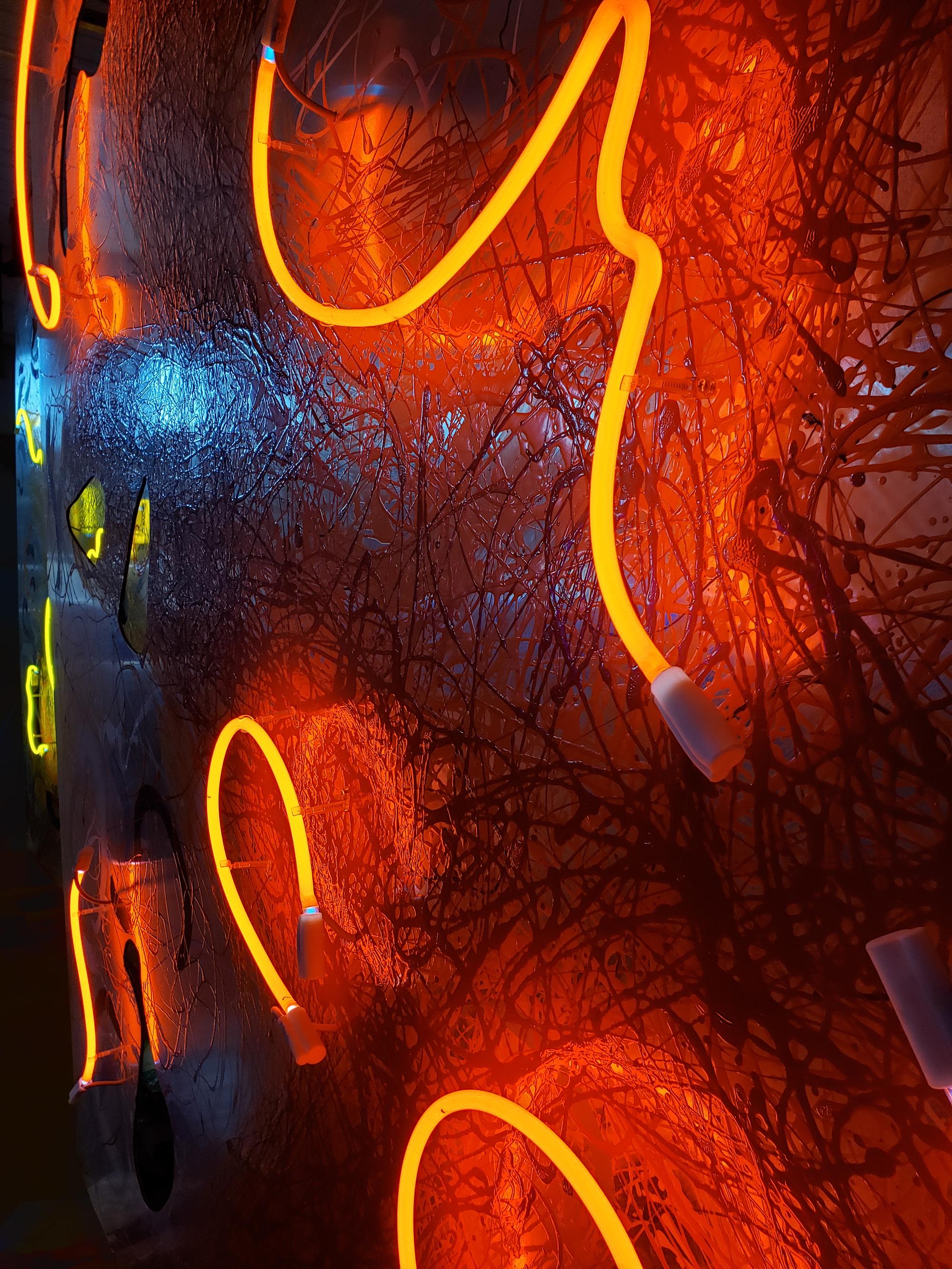 A room with a graphic print rug, brightly colored furniture, and neon mobiles