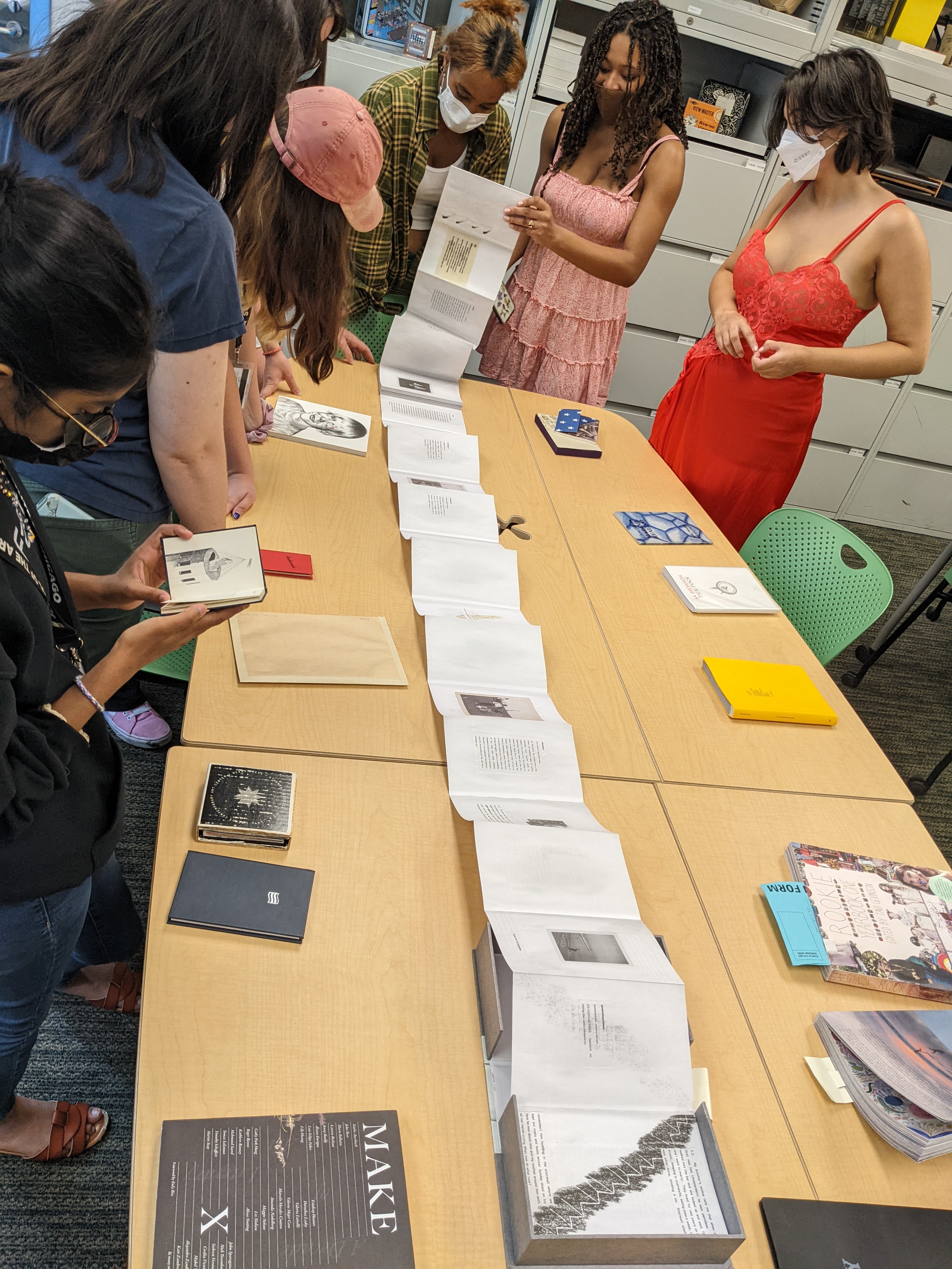 Students view a fold-out book on a table