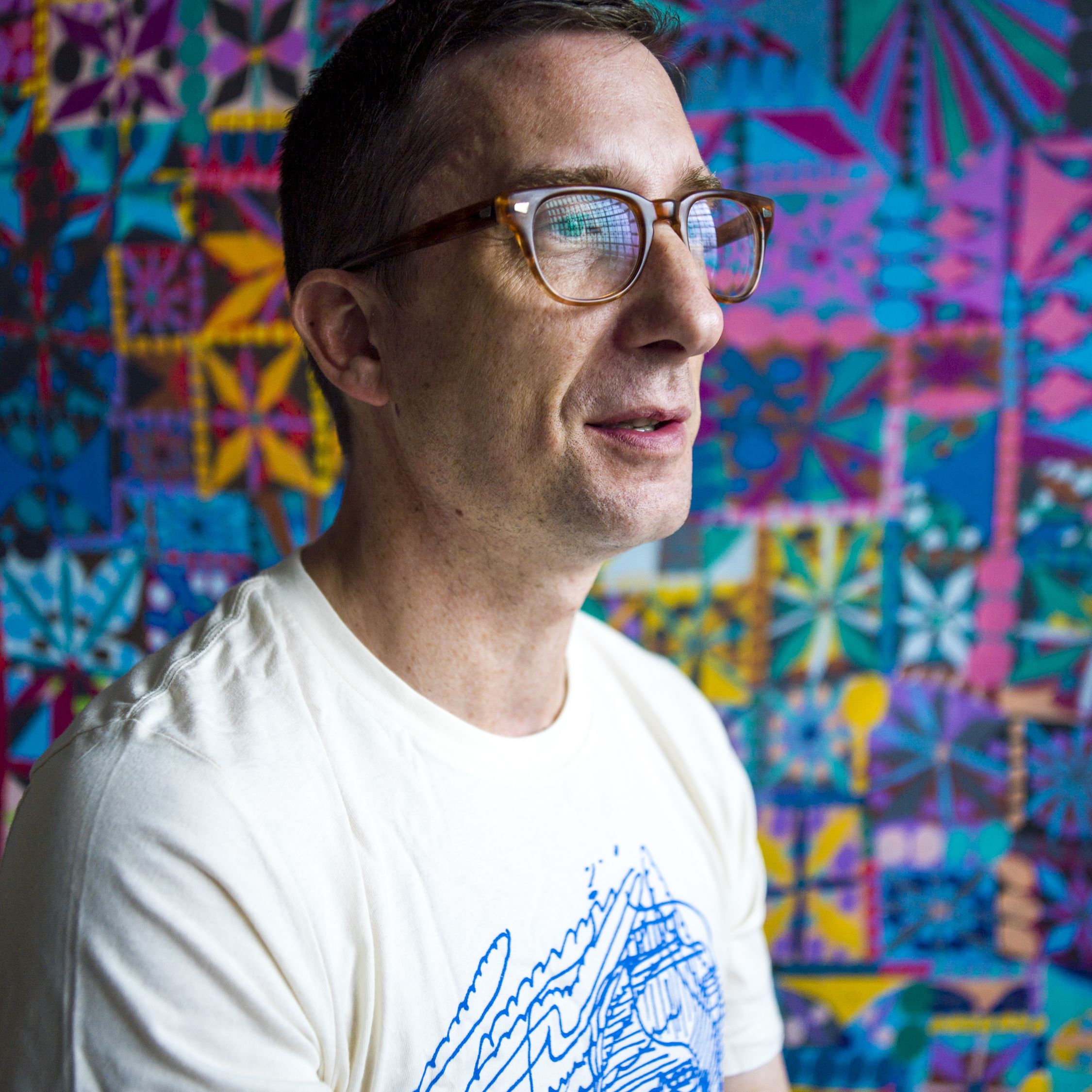 A portrait of William J. O'Brien in his studio in front of a brightly colored painting