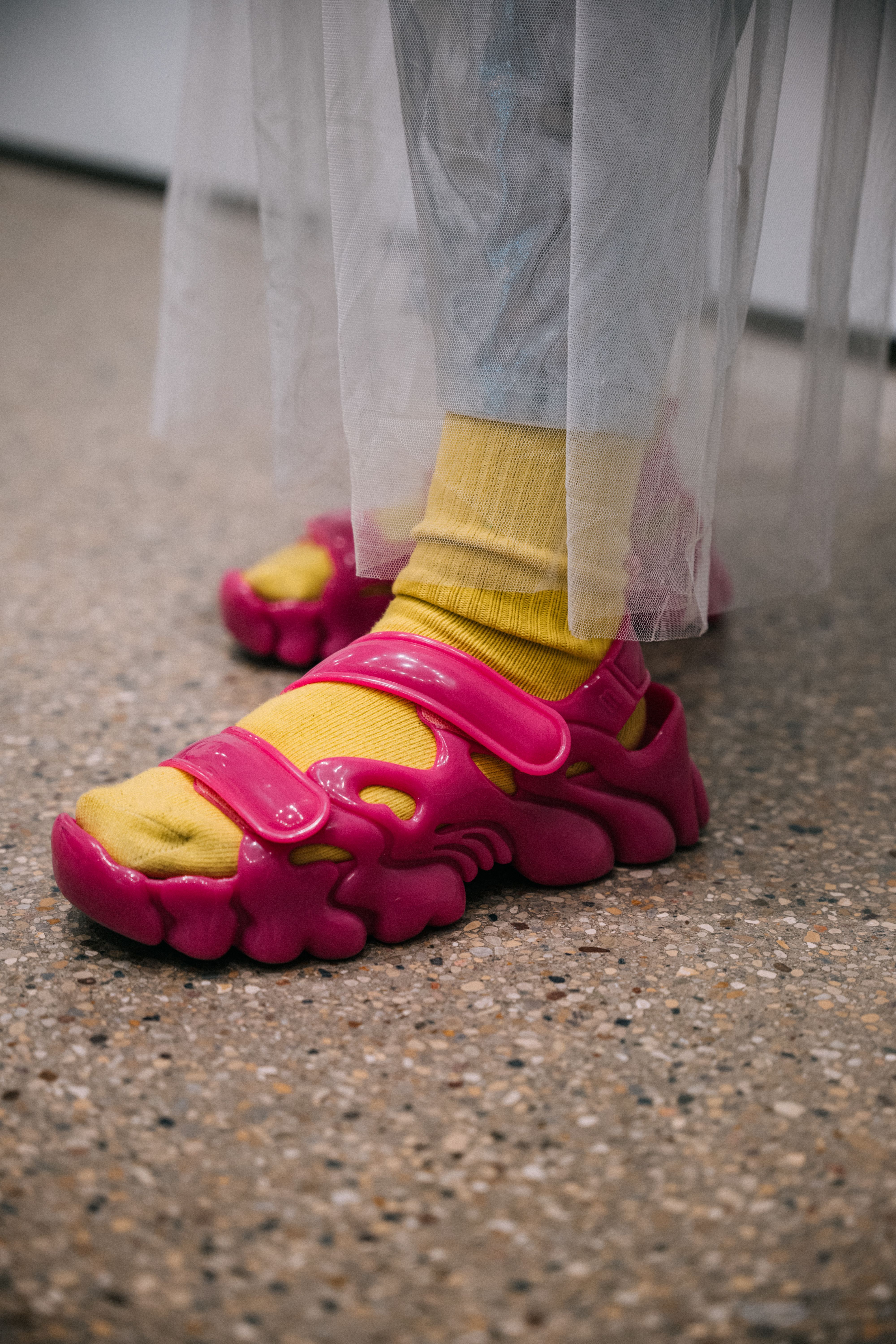 A close-up of a student's futuristic pink sandals and yellow socks.