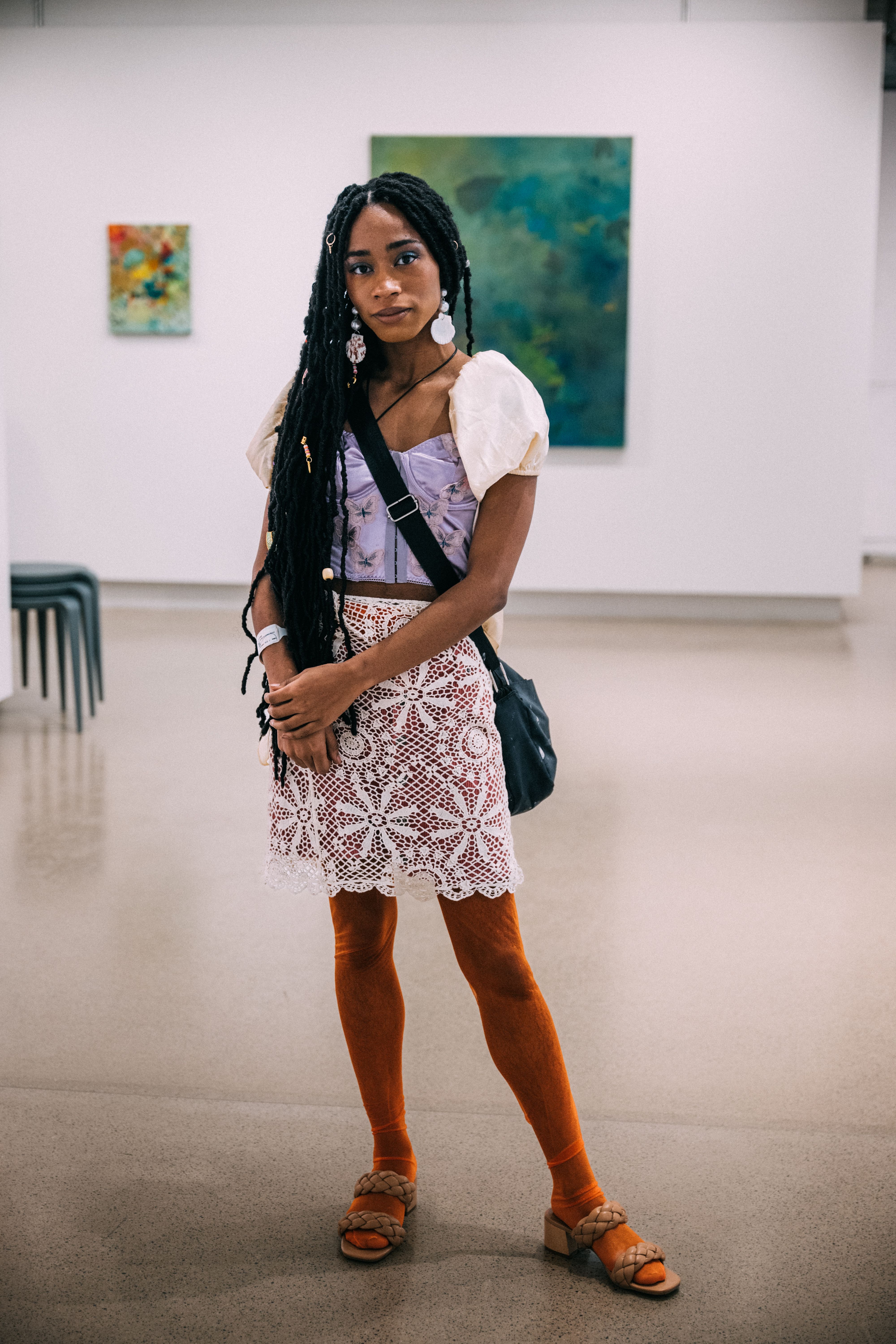 A student poses in the gallery while wearing a lace skirt and orange tights.