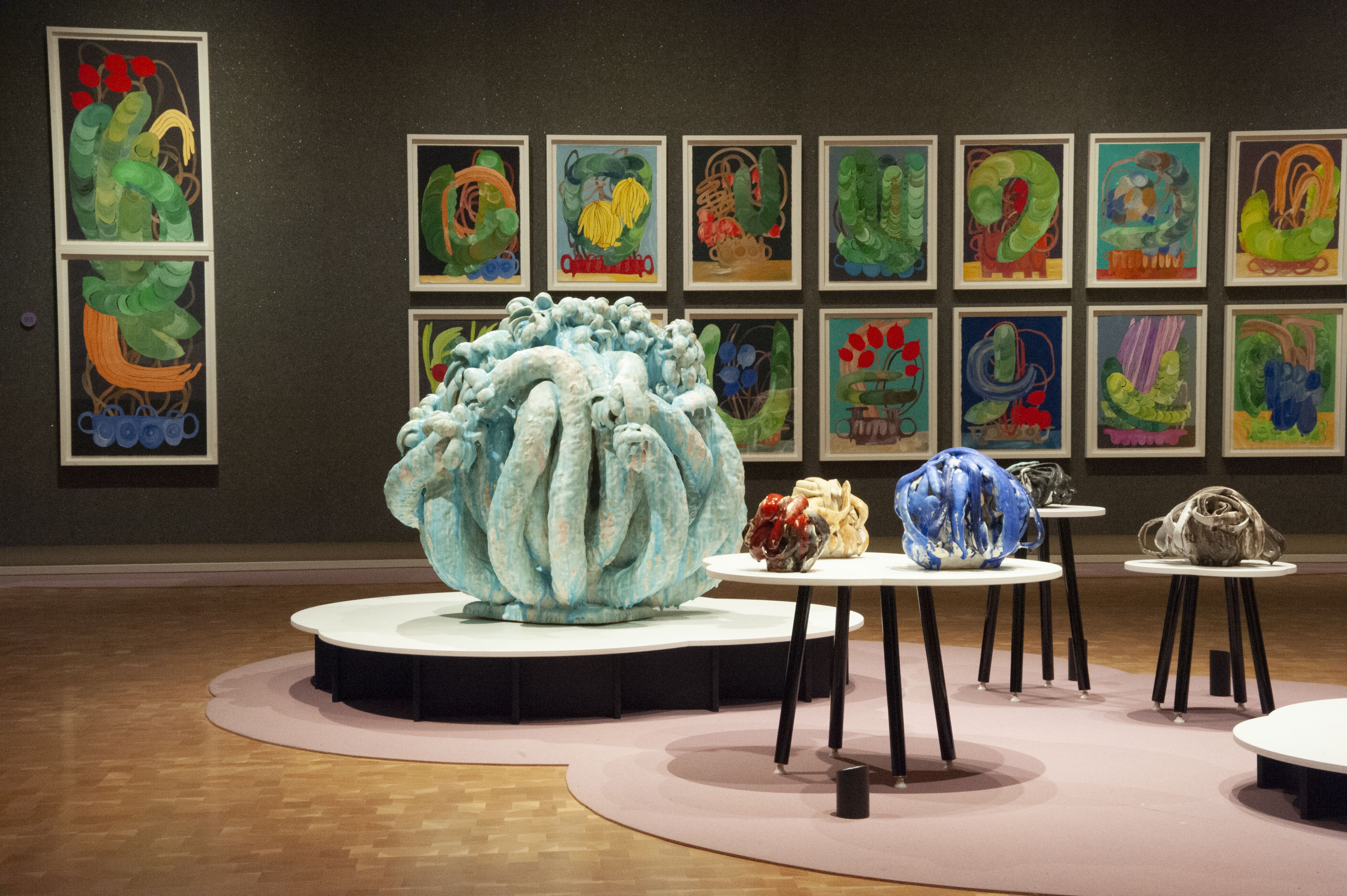 Brightly colored abstract sculptures in a gallery room with paintings on the walls