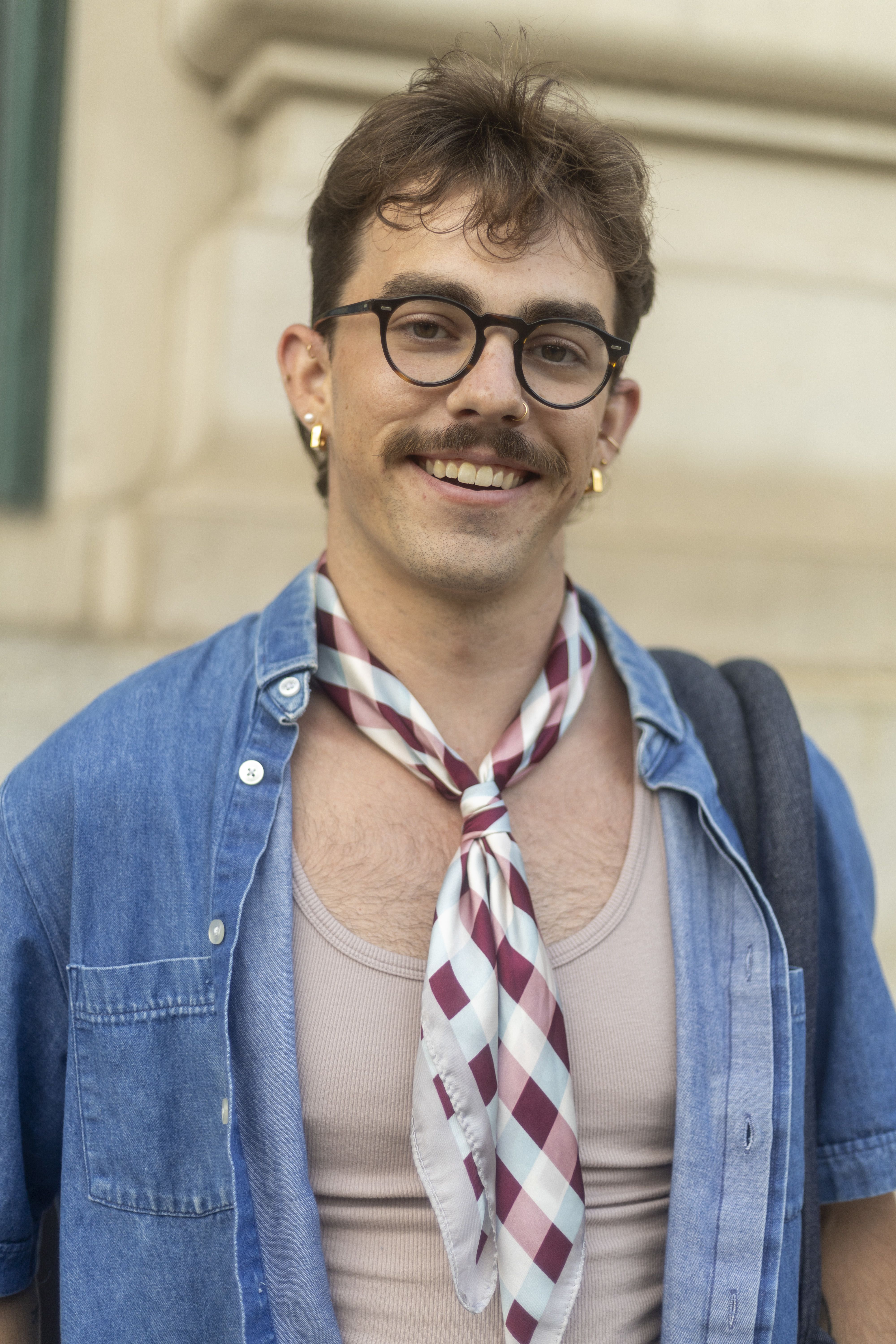 a student in glasses, a denim shirt, and a neck scarf 