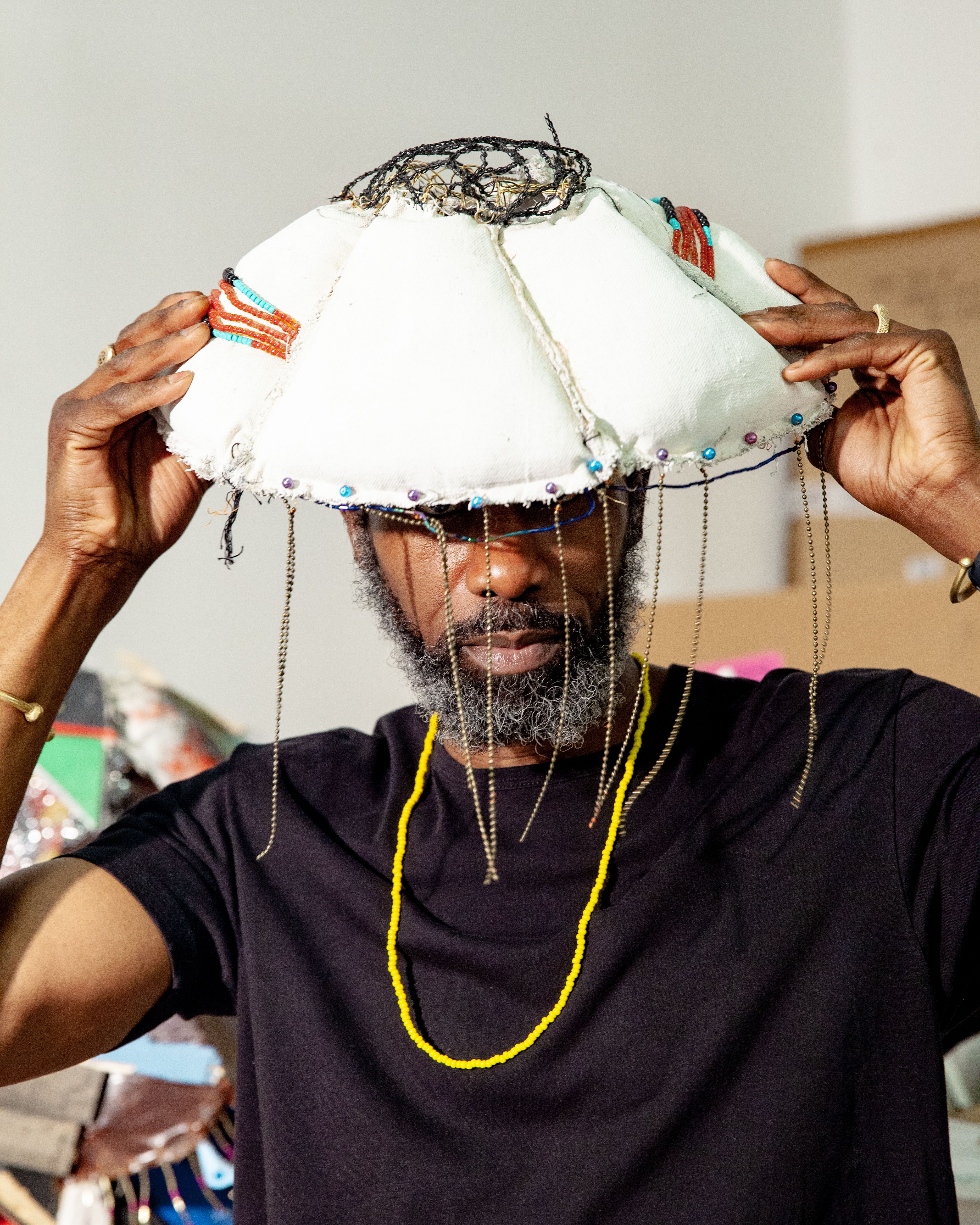 An artist putting on a lamp-shade shaped artwork