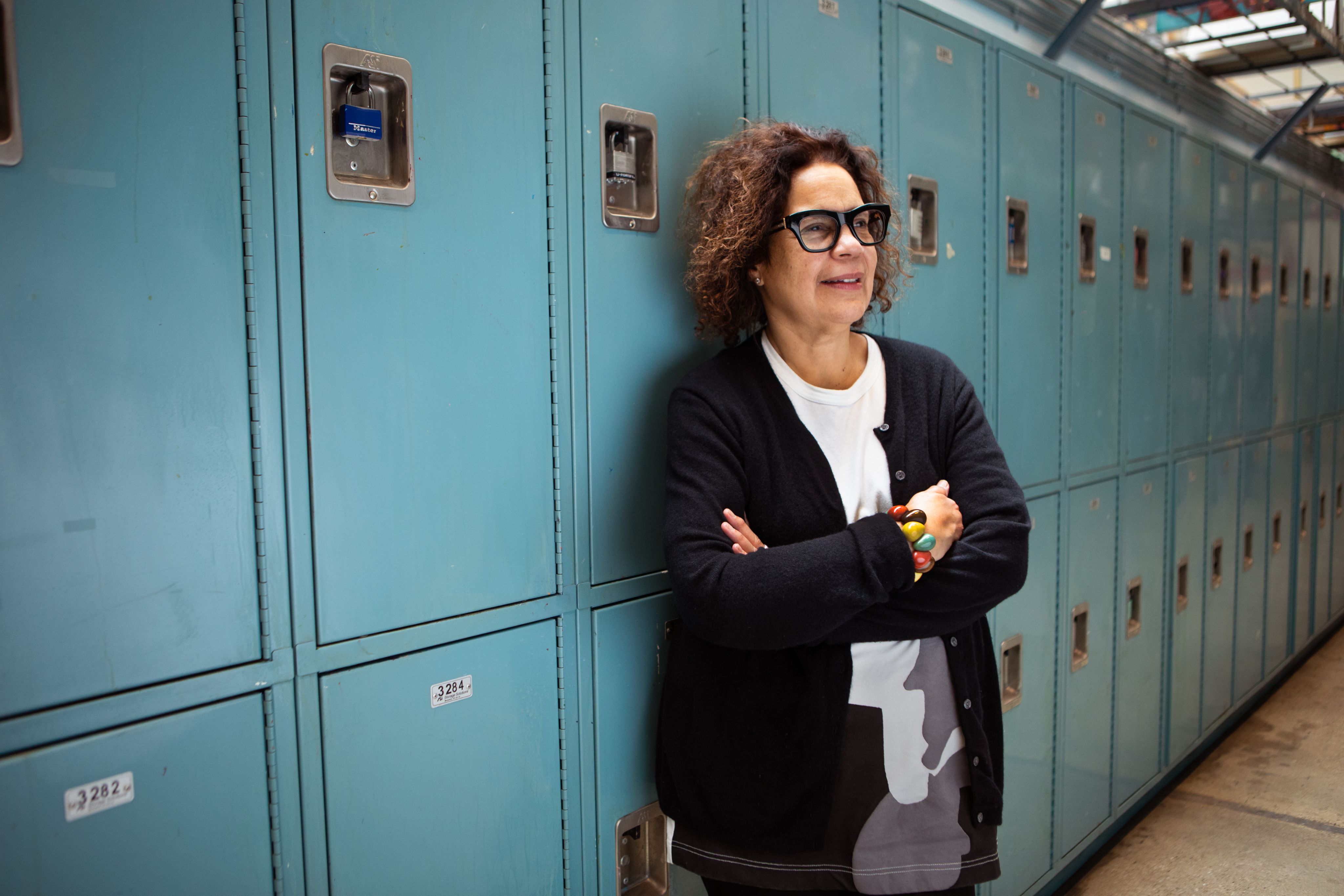 Professor Candida Alvarez stands in front of a line of blue lockers