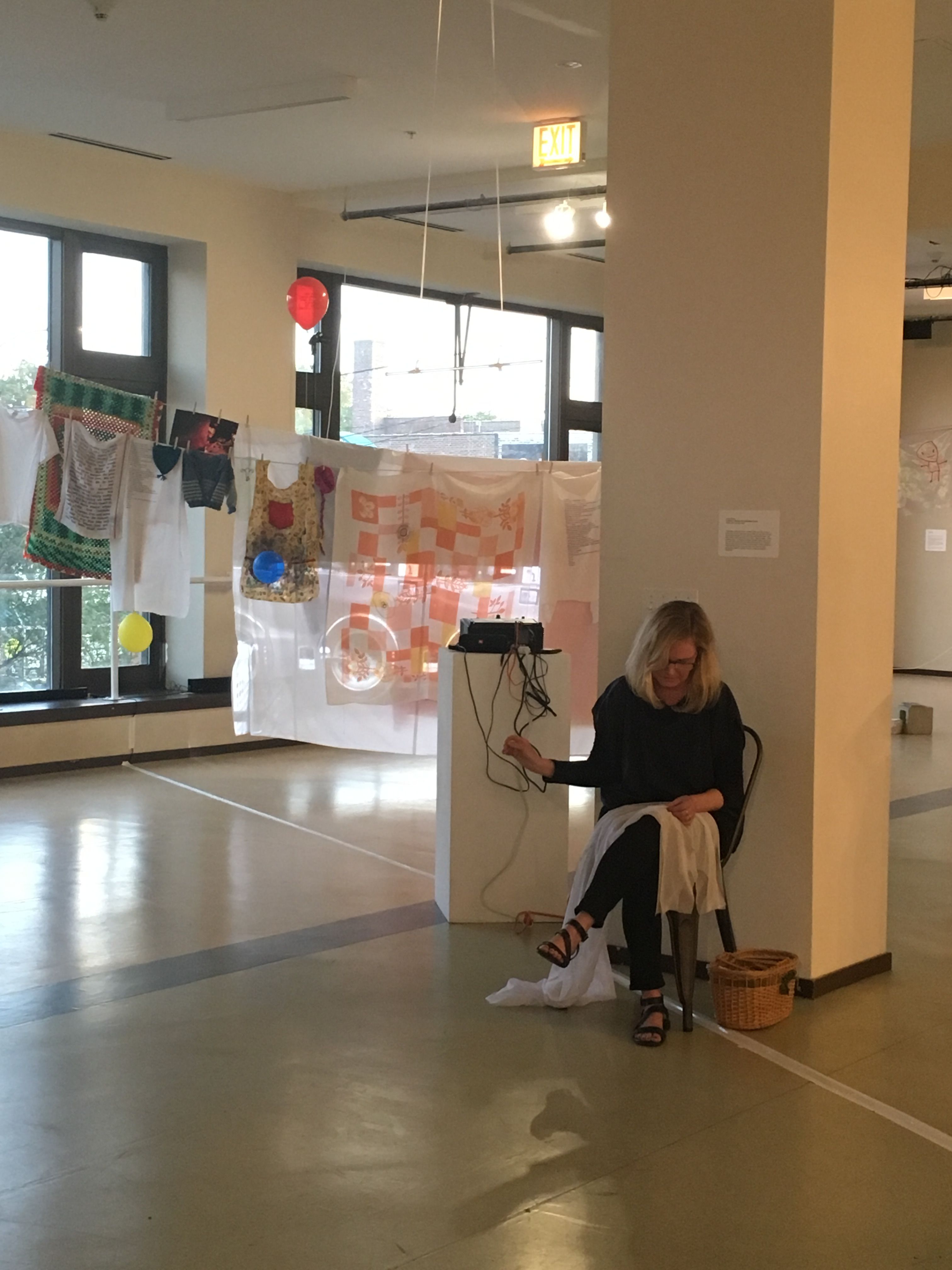 An artist sits in a gallery space