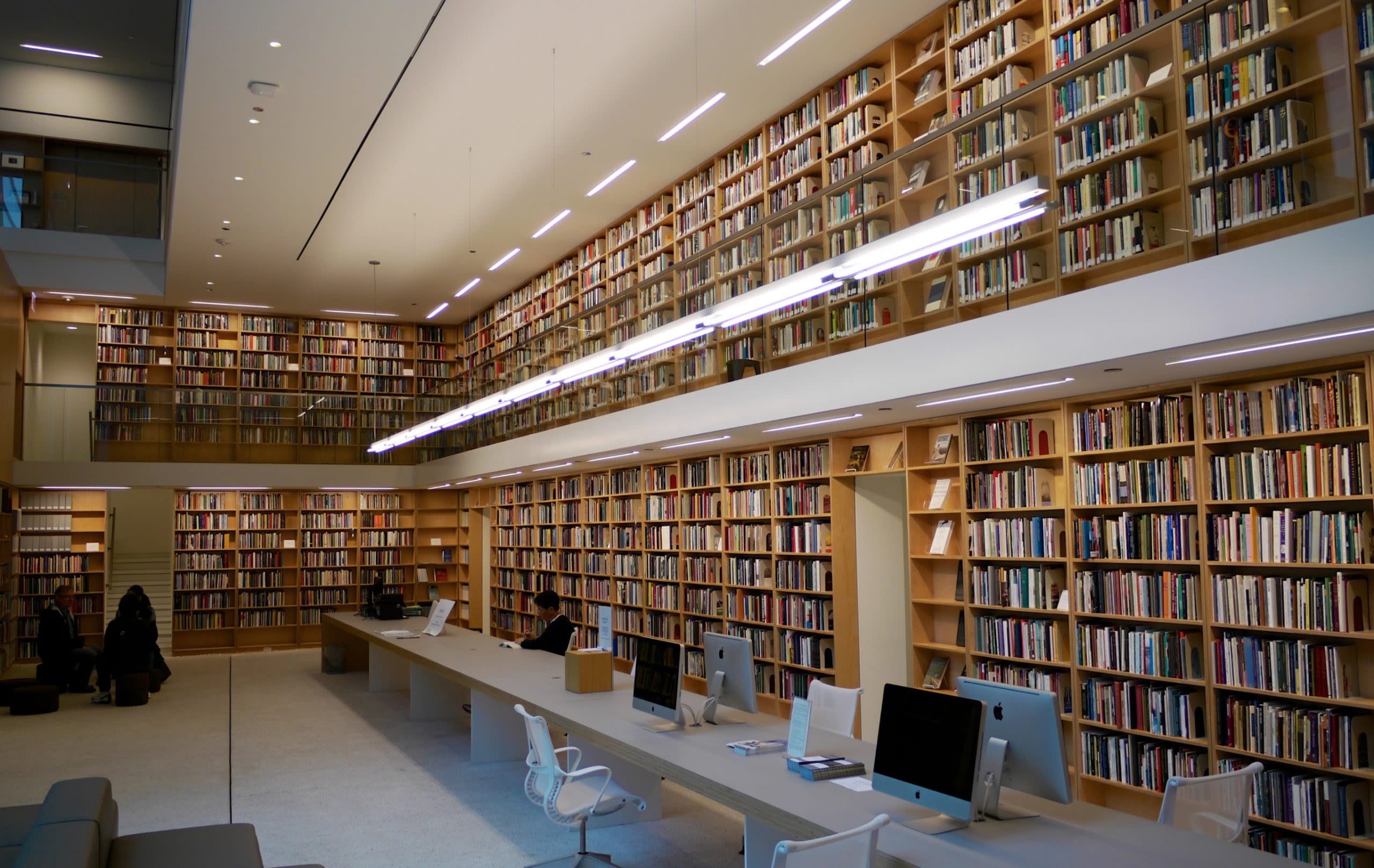Two stories of a wooden bookcases in a modern library space