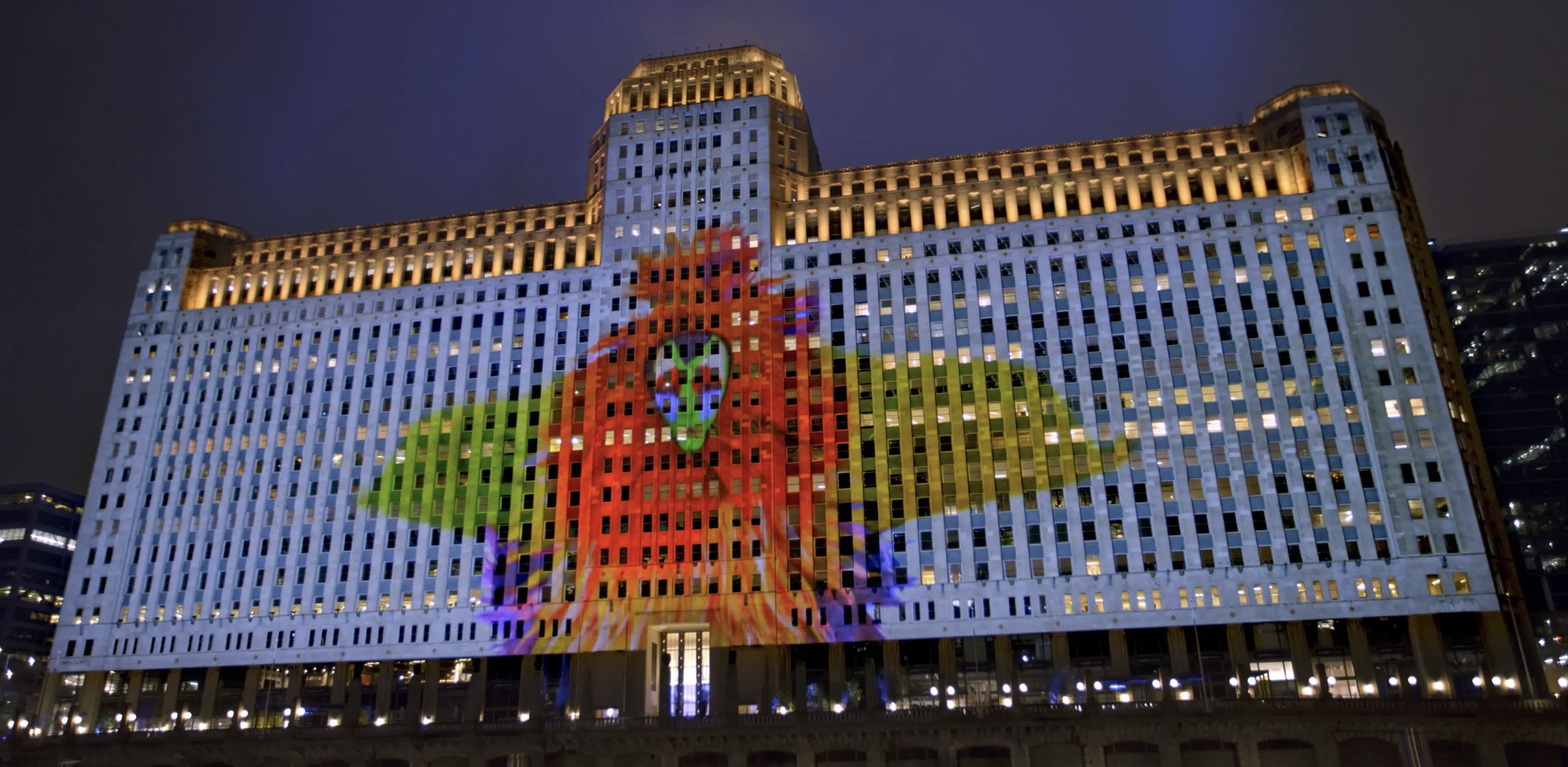 A projection on the side of Merchandise Mart of a person dressed in one of Cave's colorful Soundsuits.