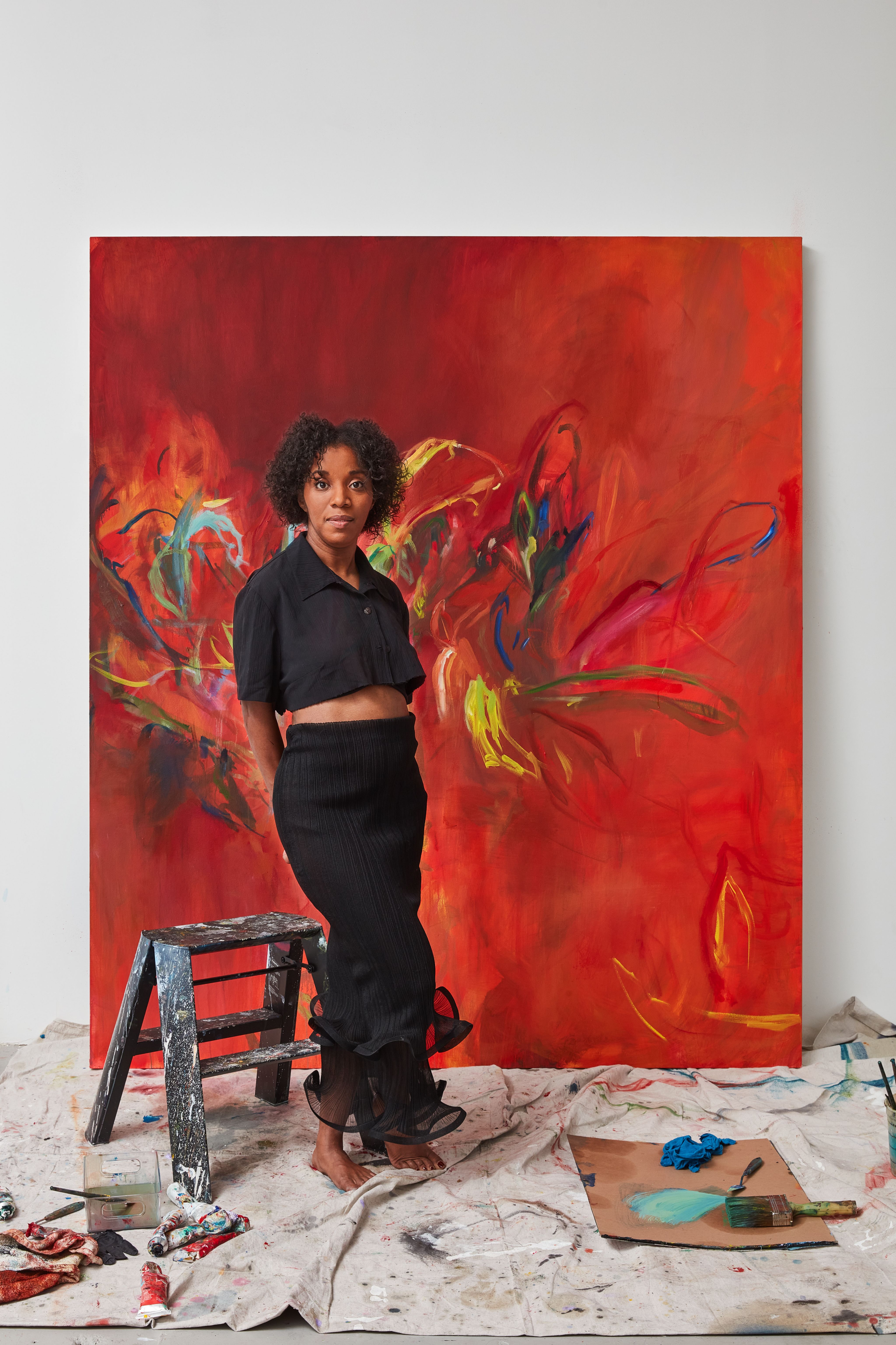 Adams poses in front of a large canvas painted in reds and yellows