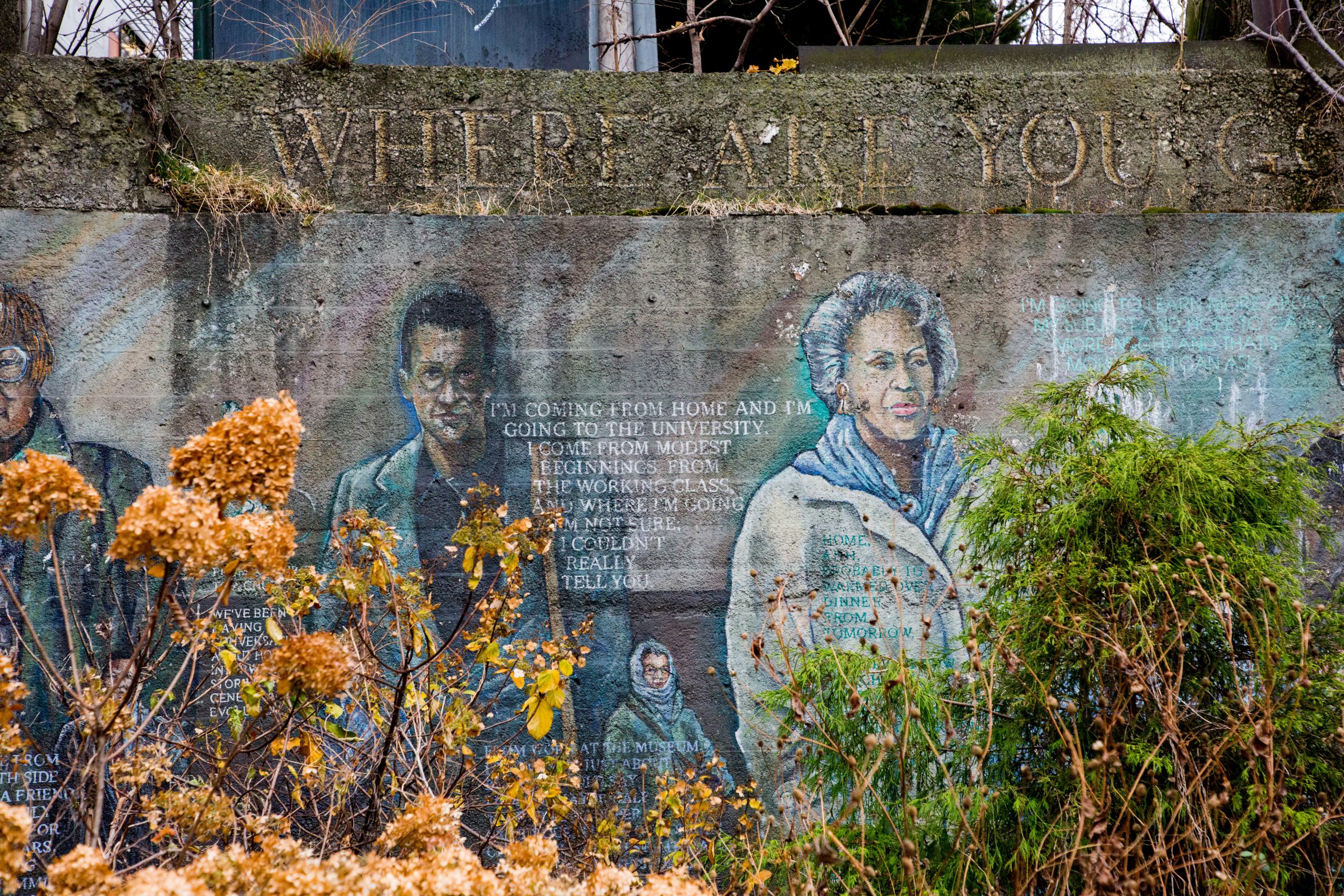 A mural of people and text behind wildflowers