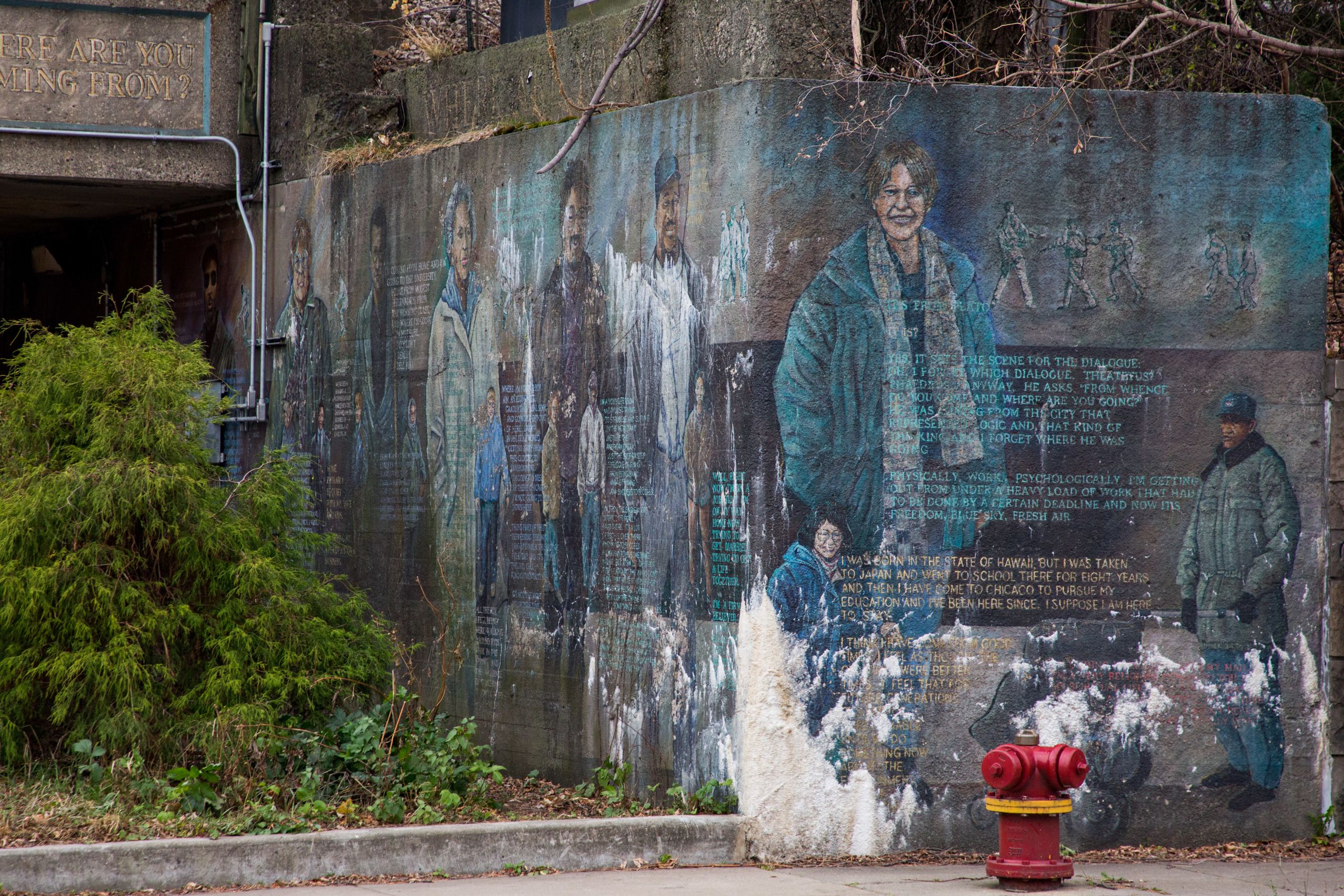 A mural under a train overpass with figures of people and text