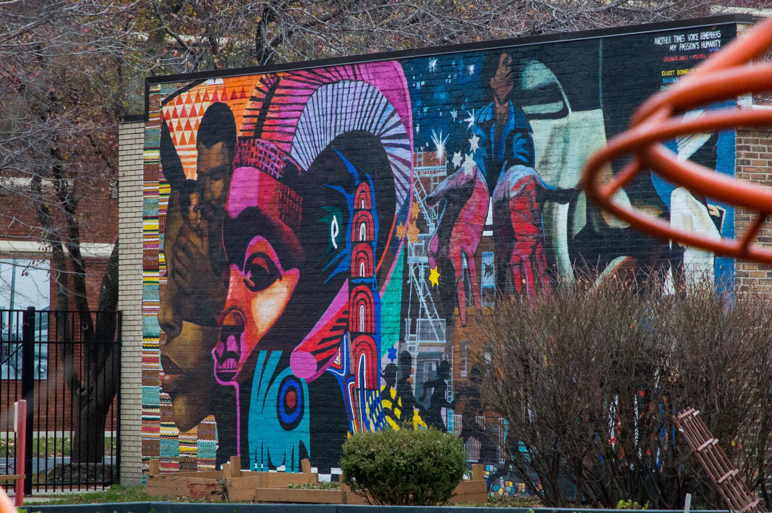 A brightly painted mural painted on a brick building behind a playground
