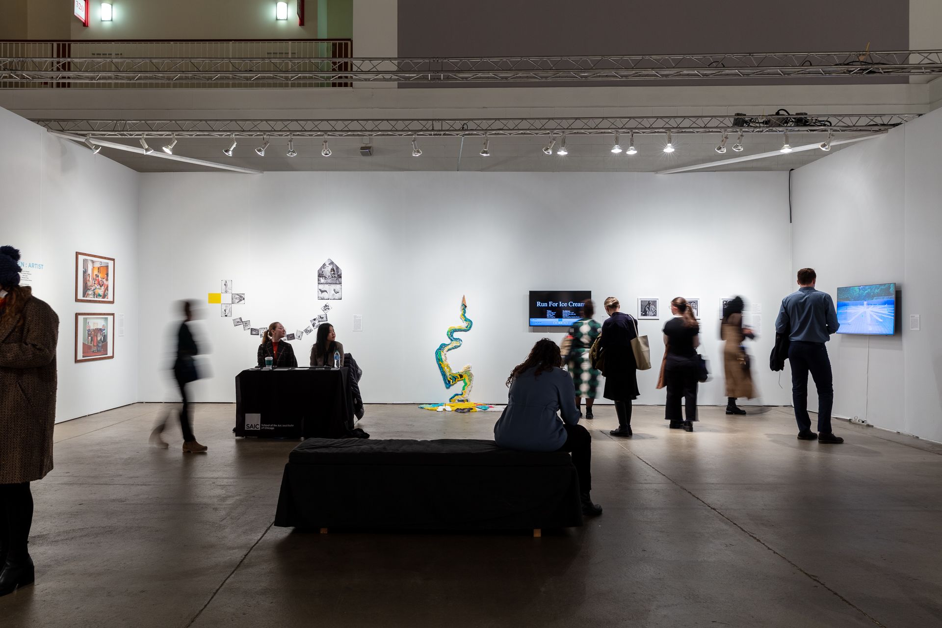 Scattered people view the art exhibited at the SAIC Alumni Booth at EXPO Chicago.