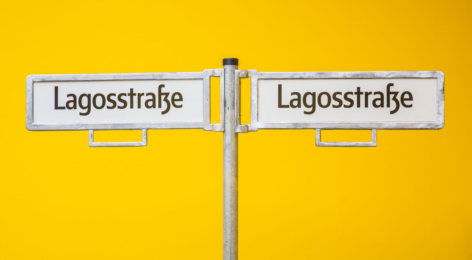 Two street signs in front of a yellow backdrop 