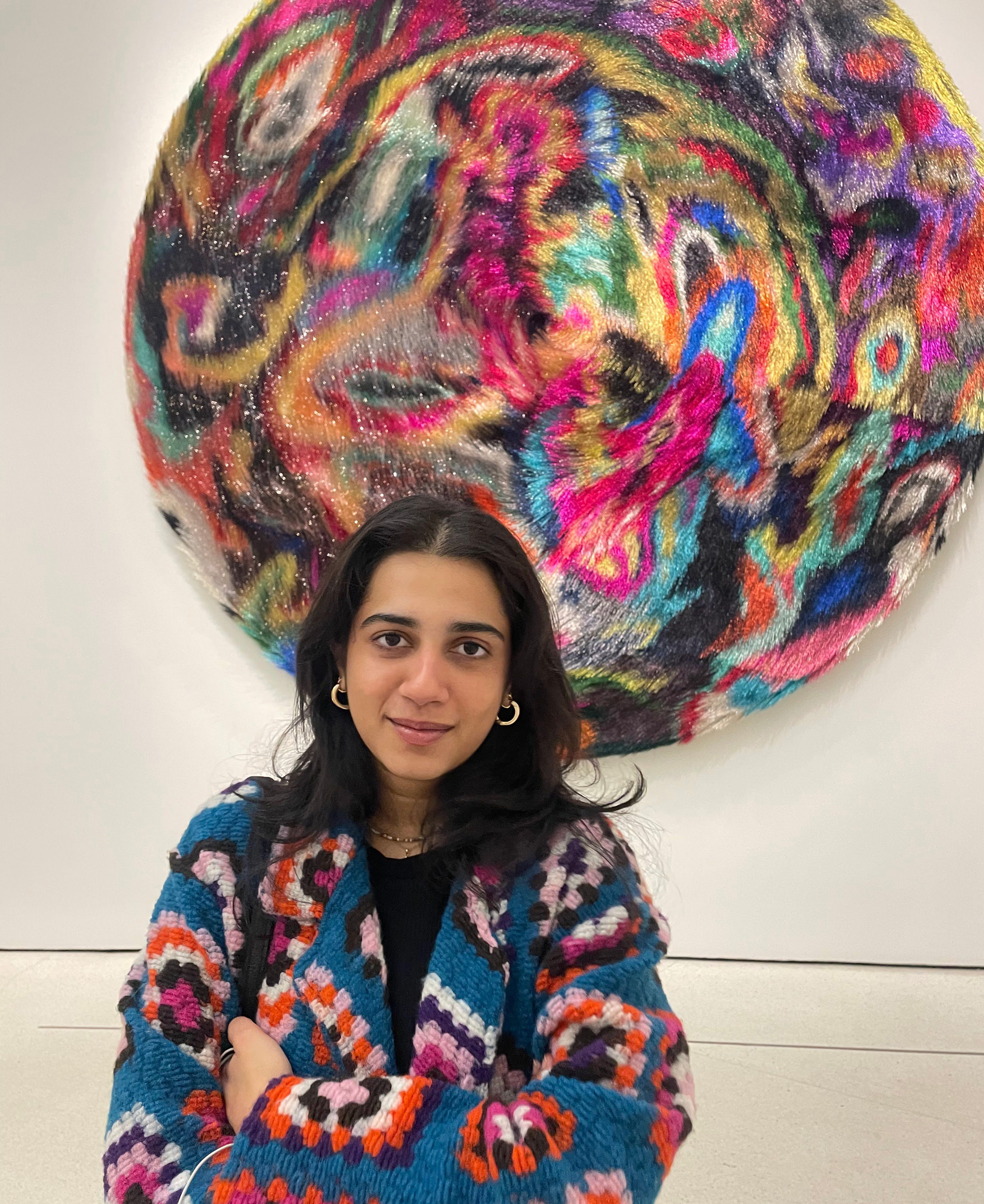 Tanya Malhotra stands in front of a colorful plus abstract artwork