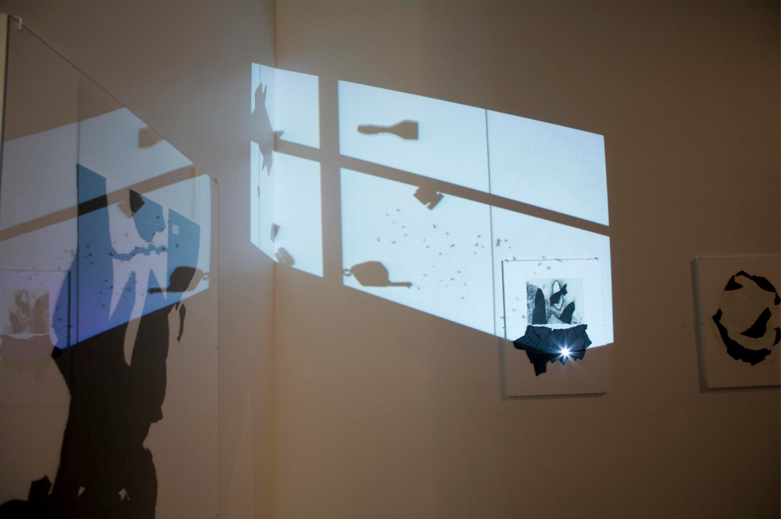 A gallery room with black and white prints on the walls and digital projections of silhouettes