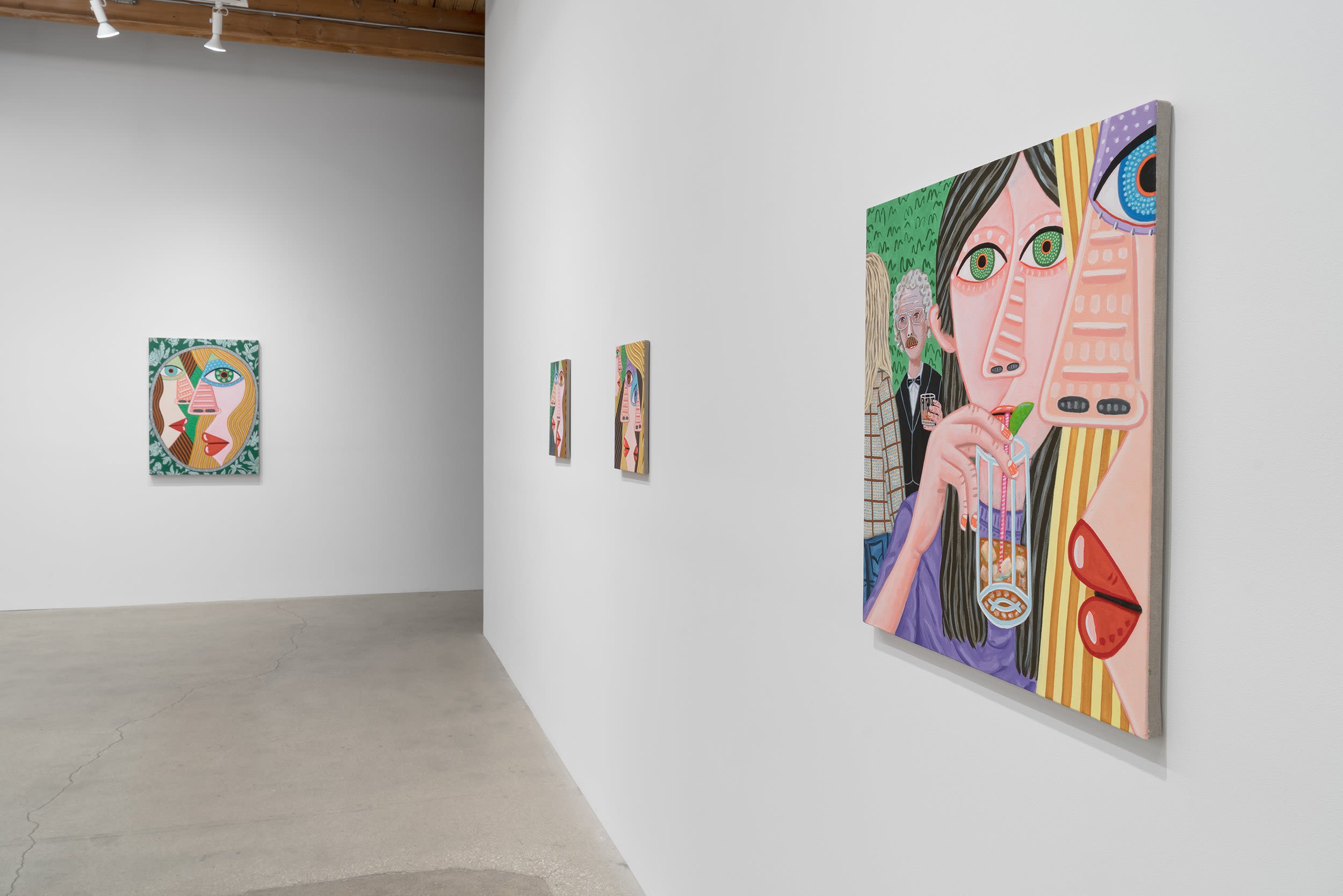A gallery space with paintings of faces