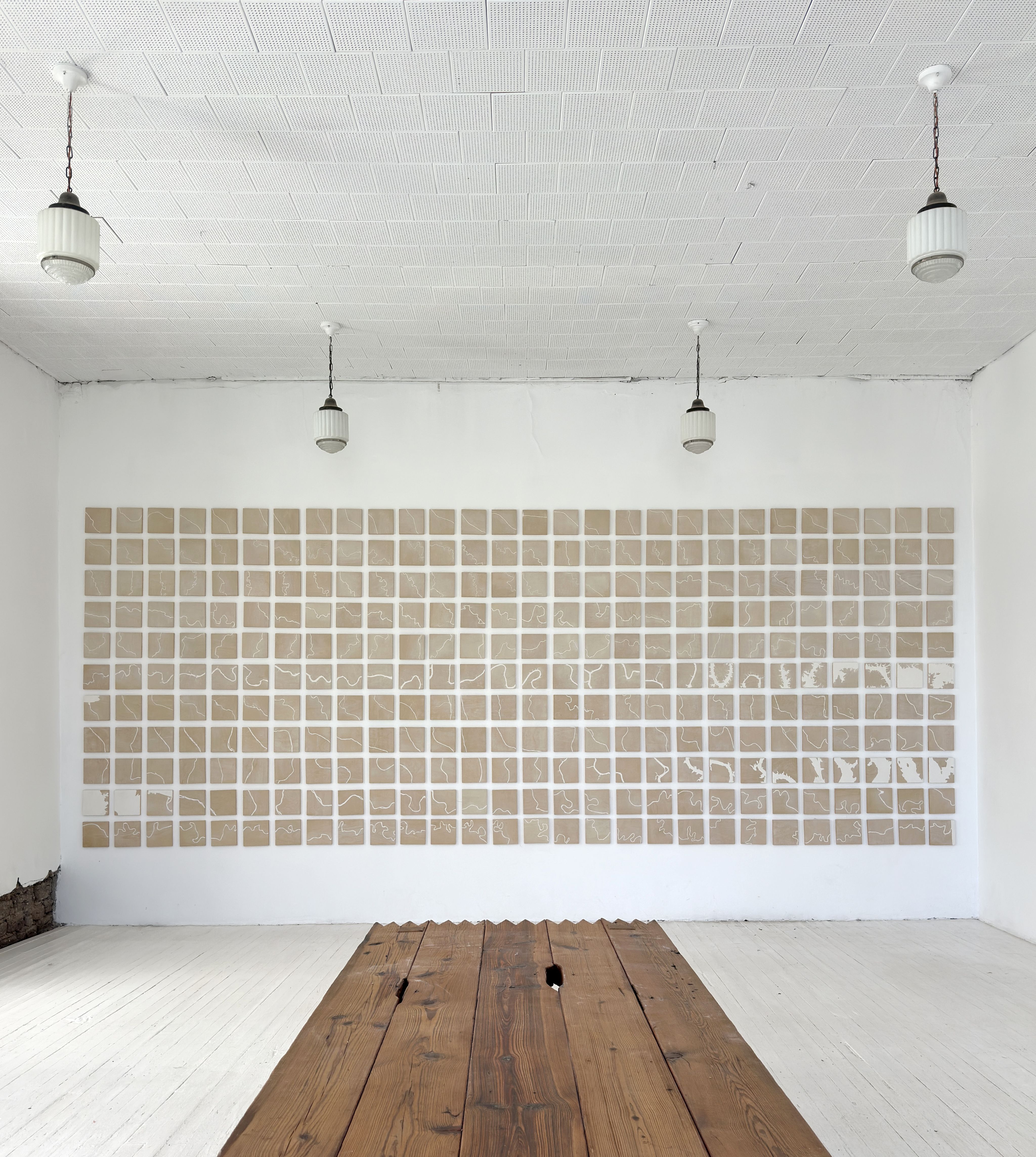 A gallery space with a wood floor and a grid-like installation