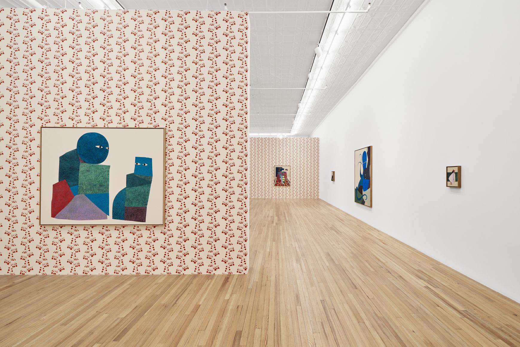 A gallery space with a wallpapered wall and hung art