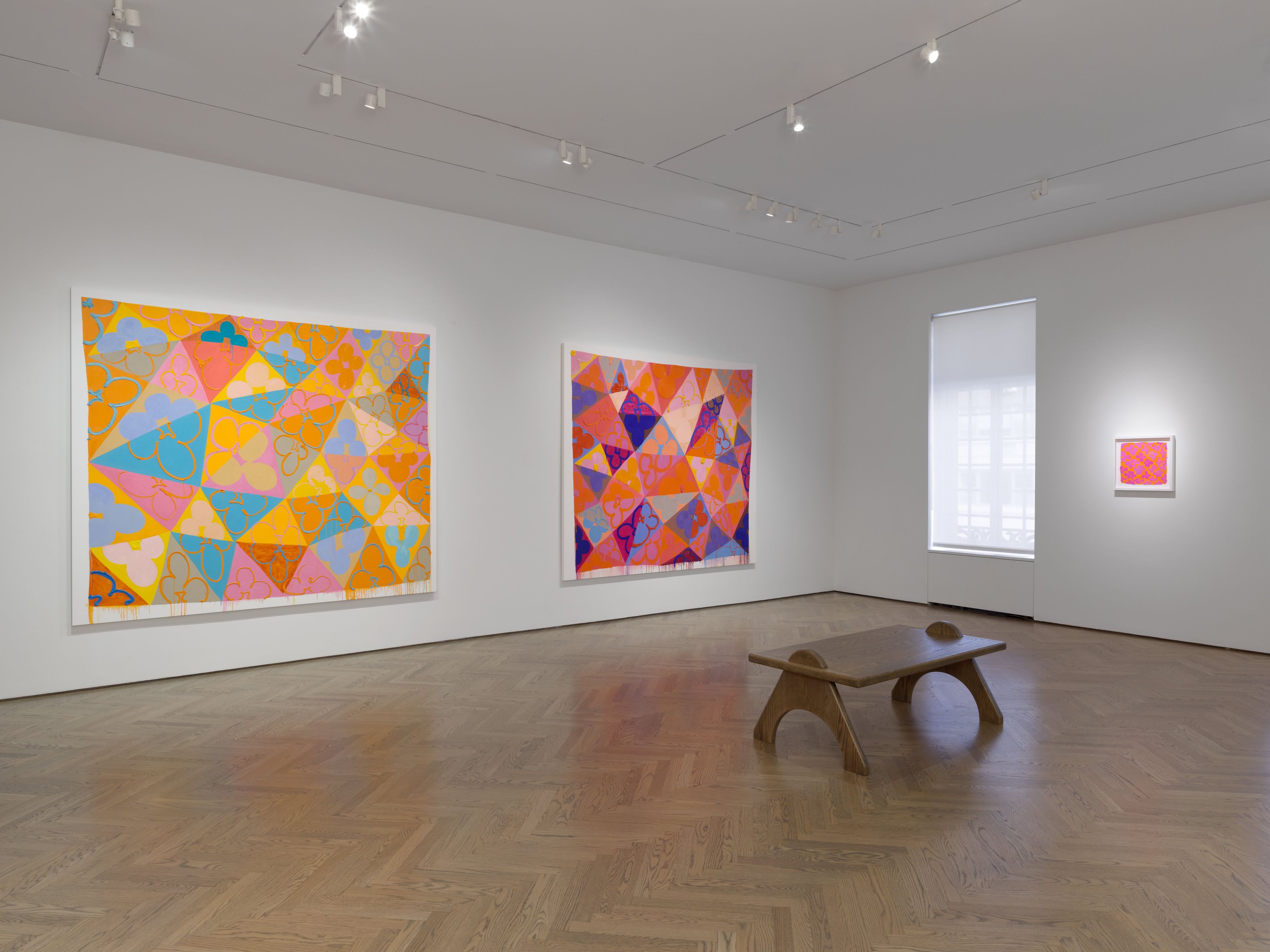 A gallery space with two bright geometric paintings