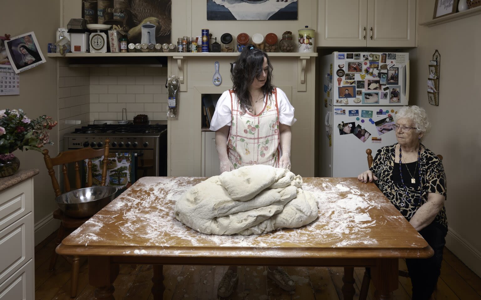 A photo of two women in front of a giant ball of dough in a kitchen