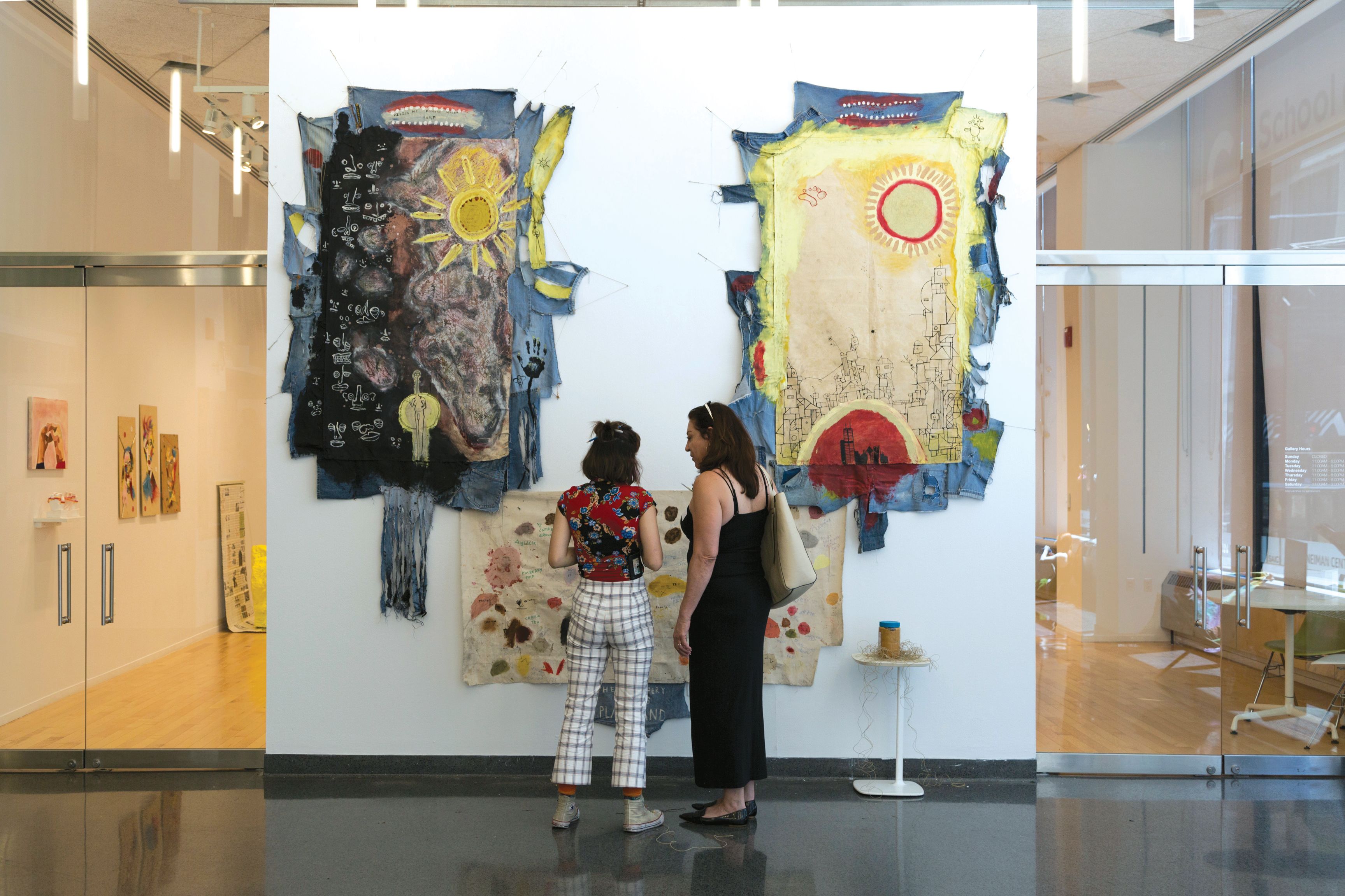 Two people stand looking at art in a gallery
