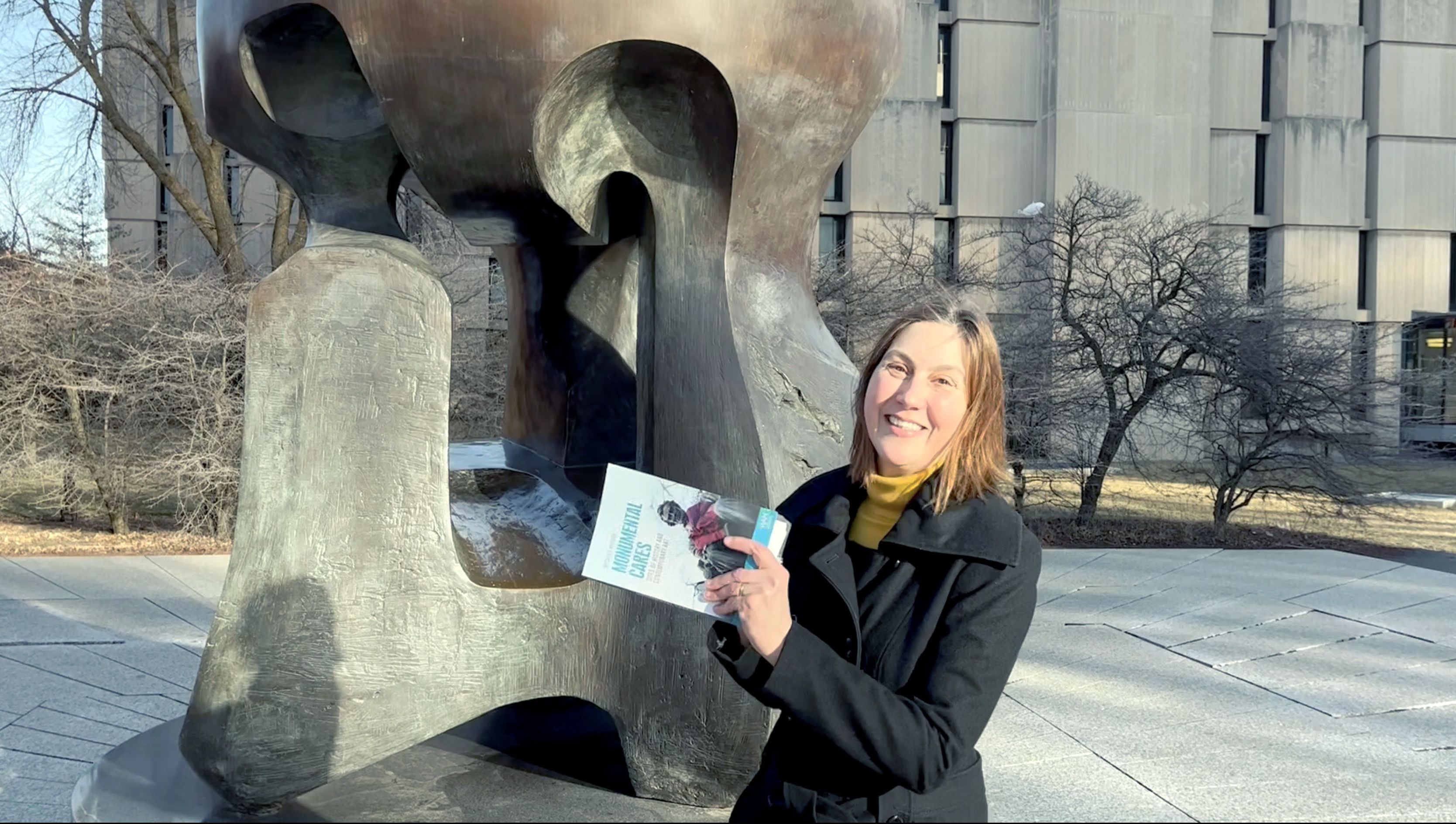 A woman holding a book in front of a monumnent.