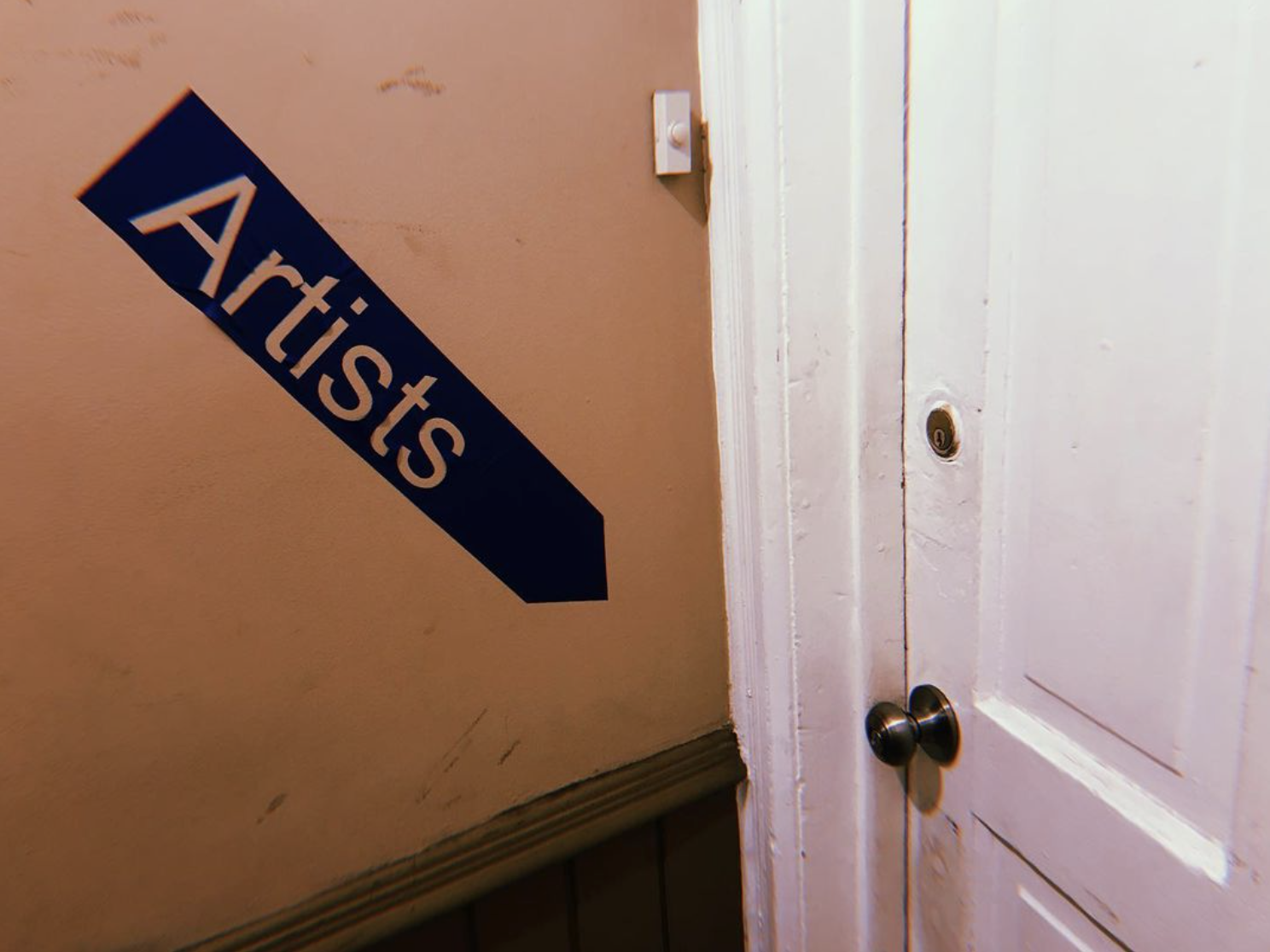 A black arrow labeled "Artists" points to a white door.