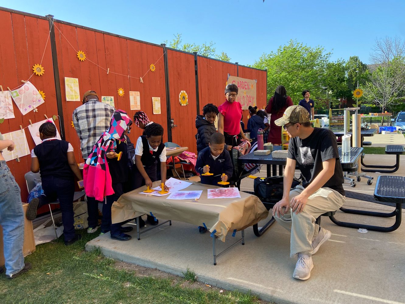 Students and volunteers make art by picnic tables